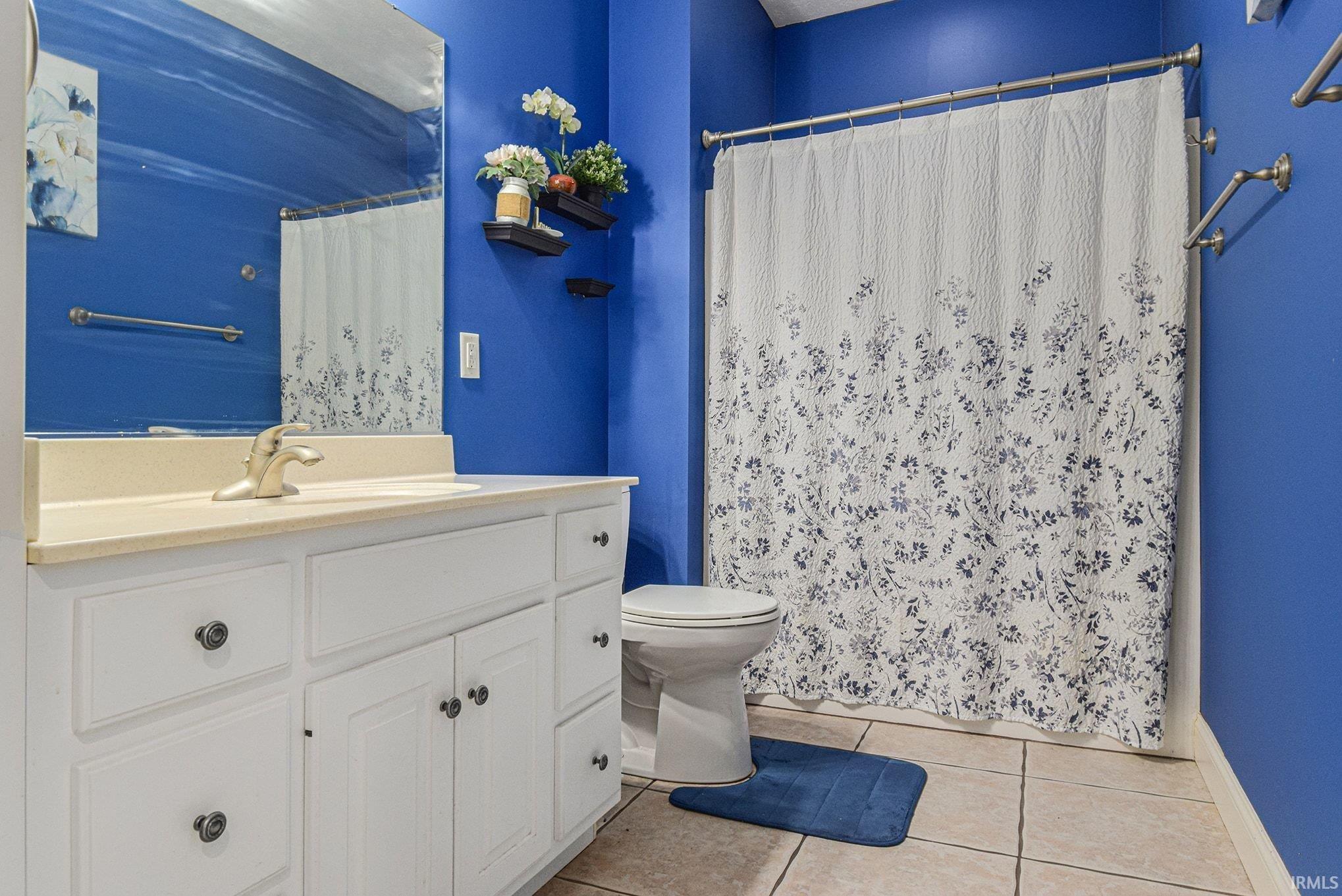 Bathroom featuring vanity, light tile patterned flooring, and a shower with shower curtain
