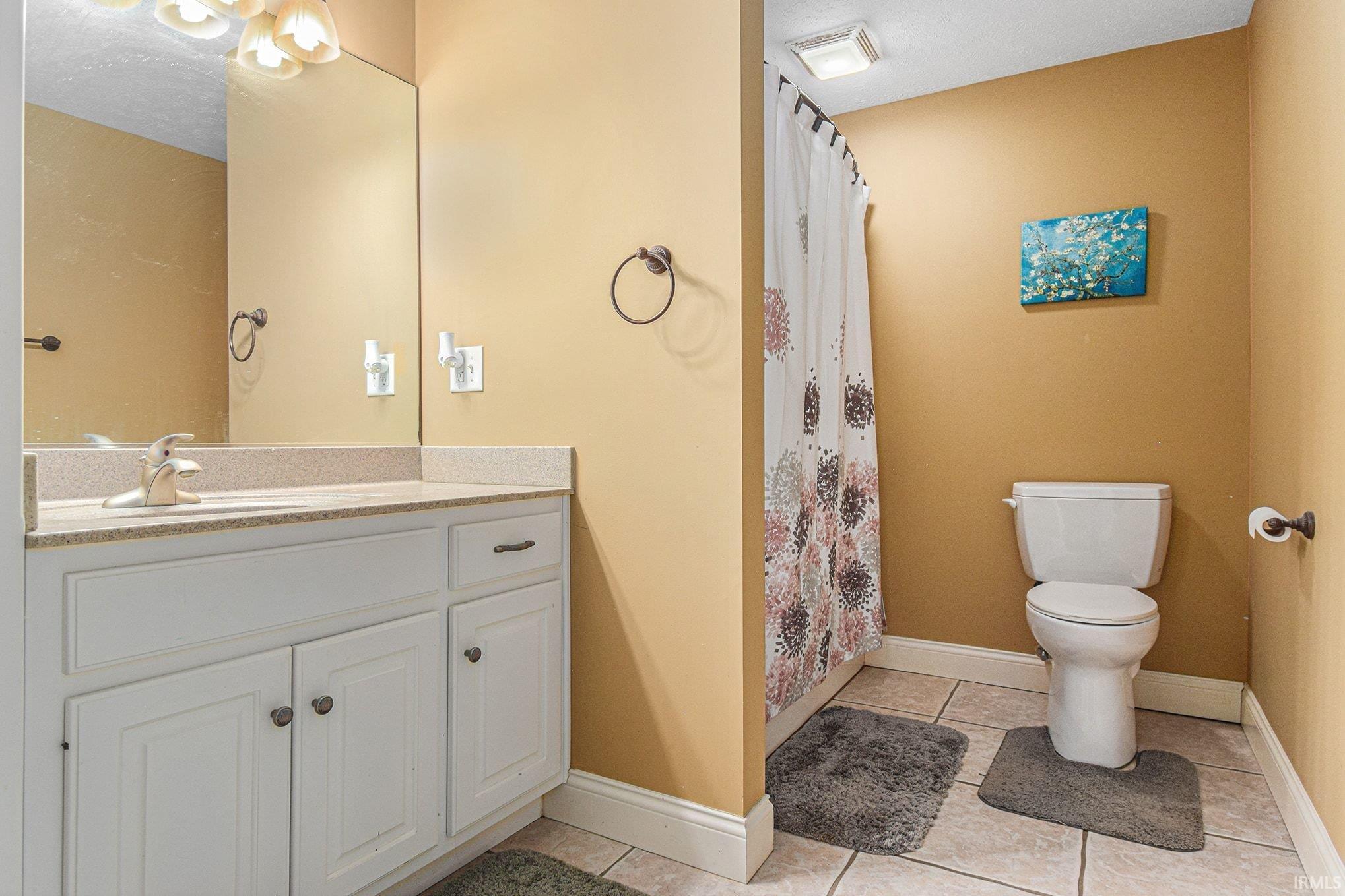 Bathroom featuring a shower with curtain, vanity, and light tile patterned floors