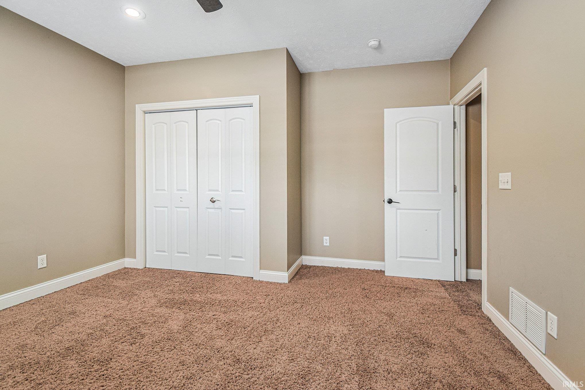 Unfurnished bedroom with a closet, carpet flooring, and ceiling fan