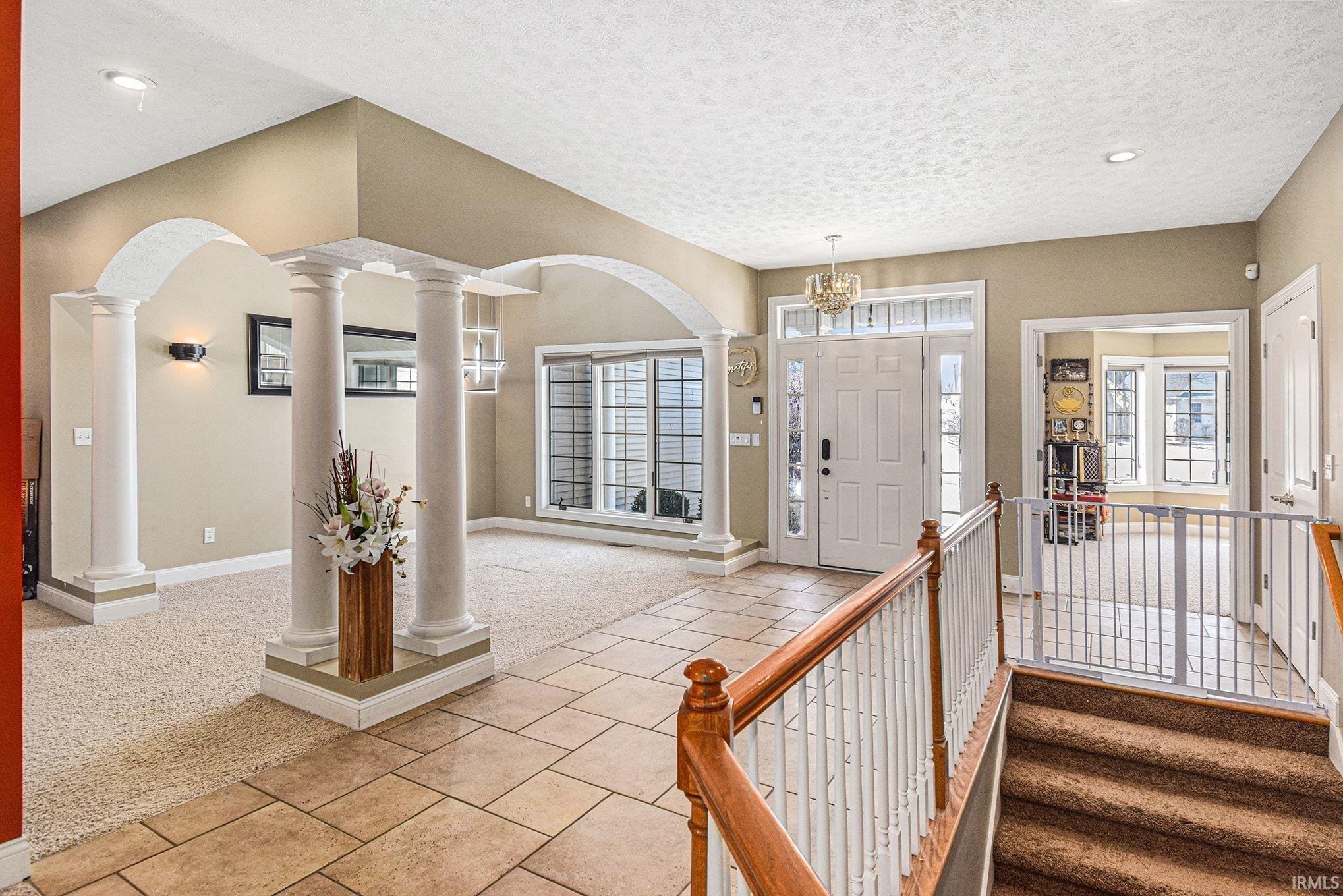 Carpeted foyer entrance featuring tile patterned floors, a textured ceiling, and recessed lighting