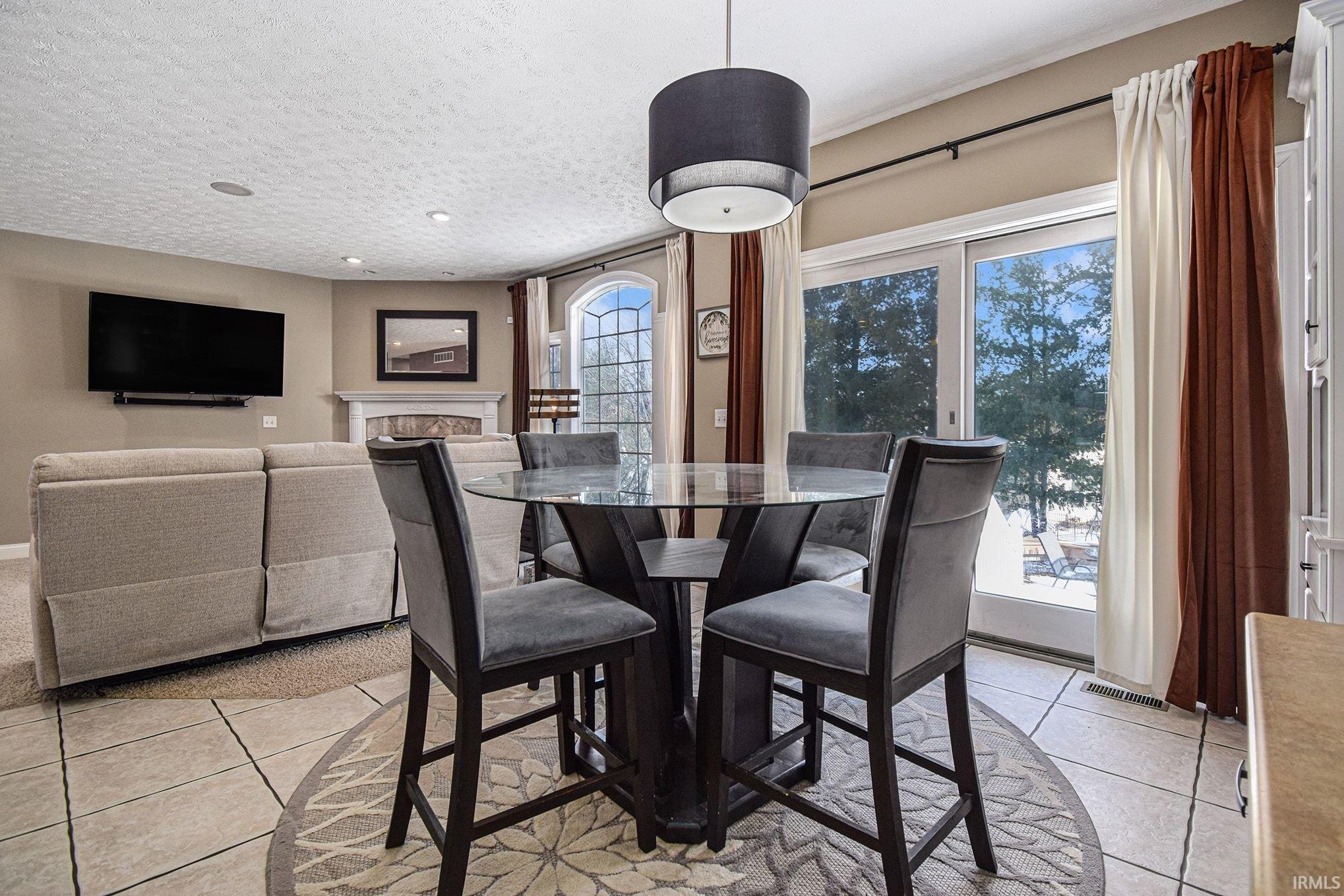 Dining area with light tile patterned flooring, a fireplace, a textured ceiling, and recessed lighting