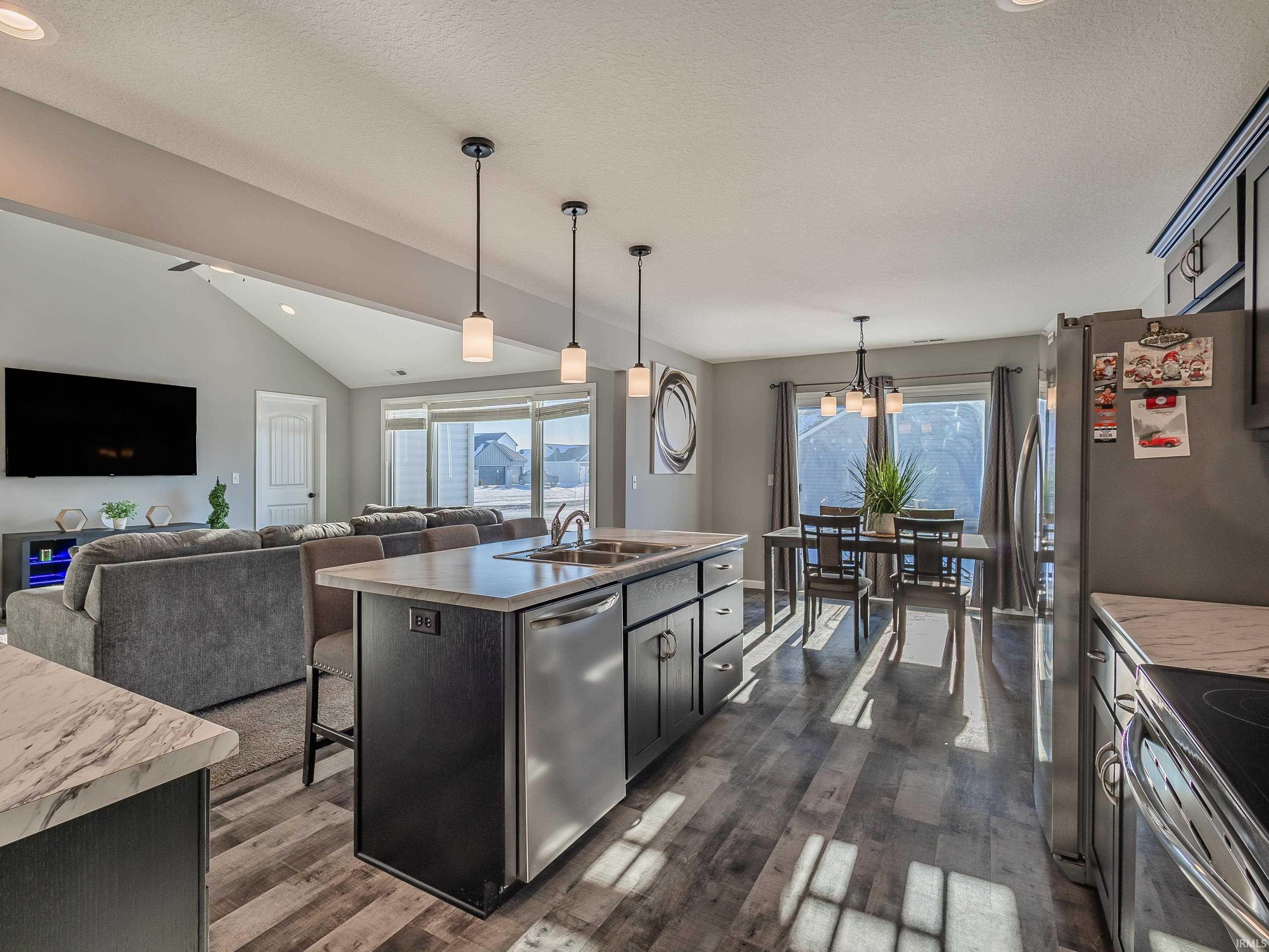 Kitchen with hanging light fixtures, a kitchen island with sink, a breakfast nook, open floor plan, and lofted ceiling