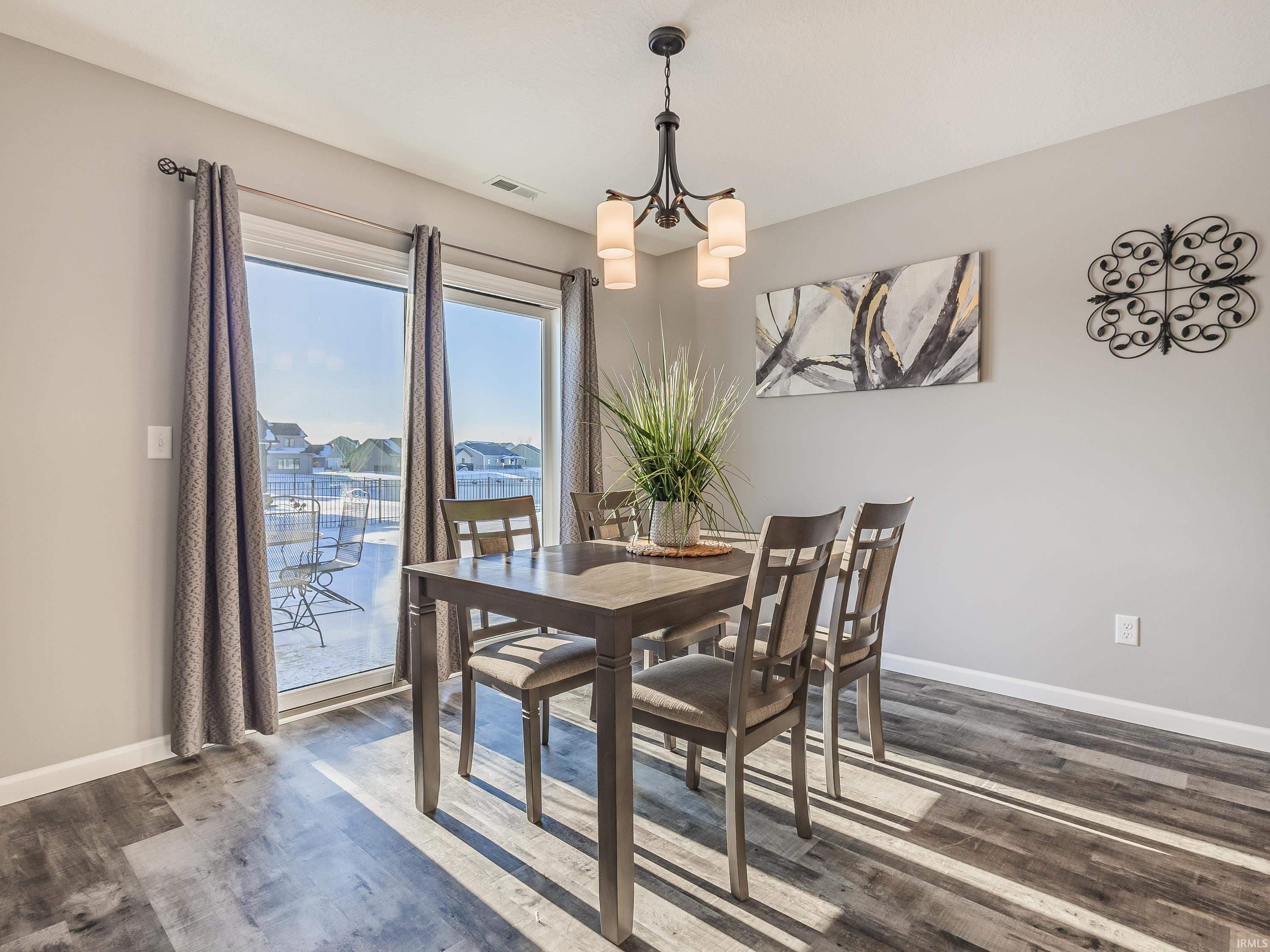 Dining space with dark wood finished floors and a chandelier