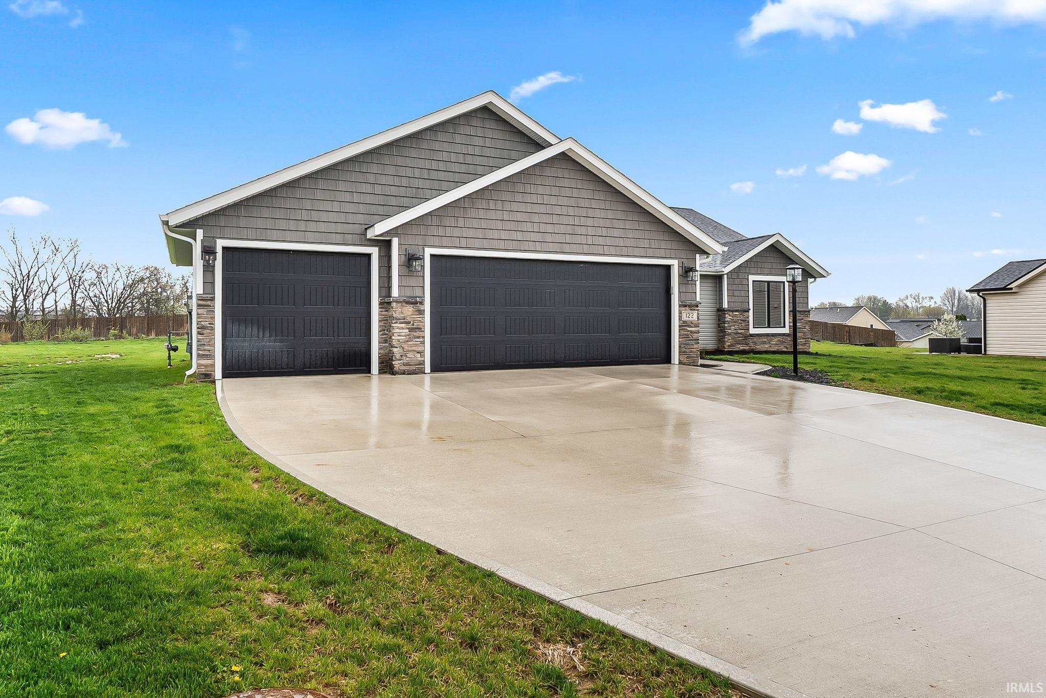 Craftsman inspired home with stone siding, a front yard, a garage, and driveway