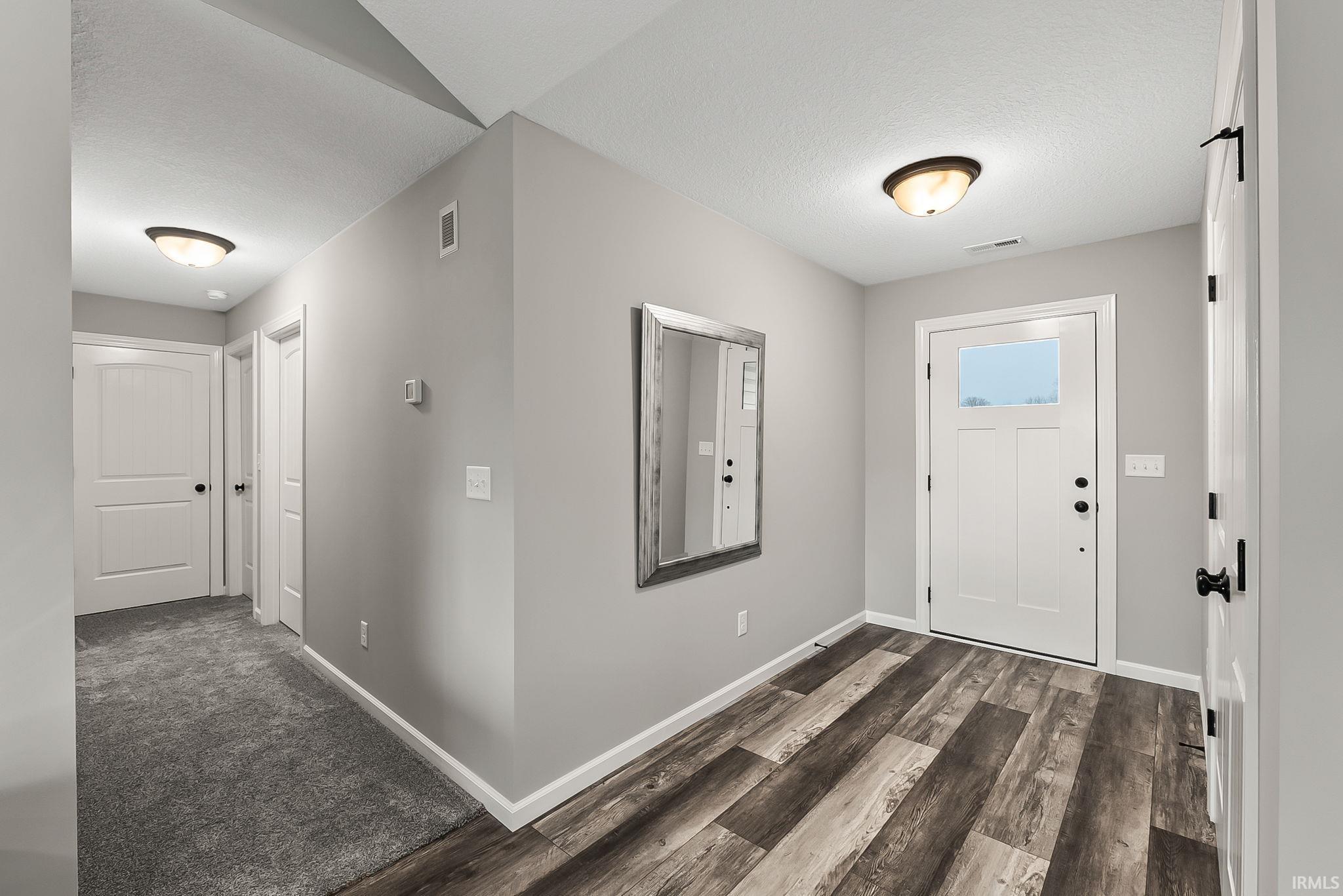 Entryway with dark wood finished floors and a textured ceiling