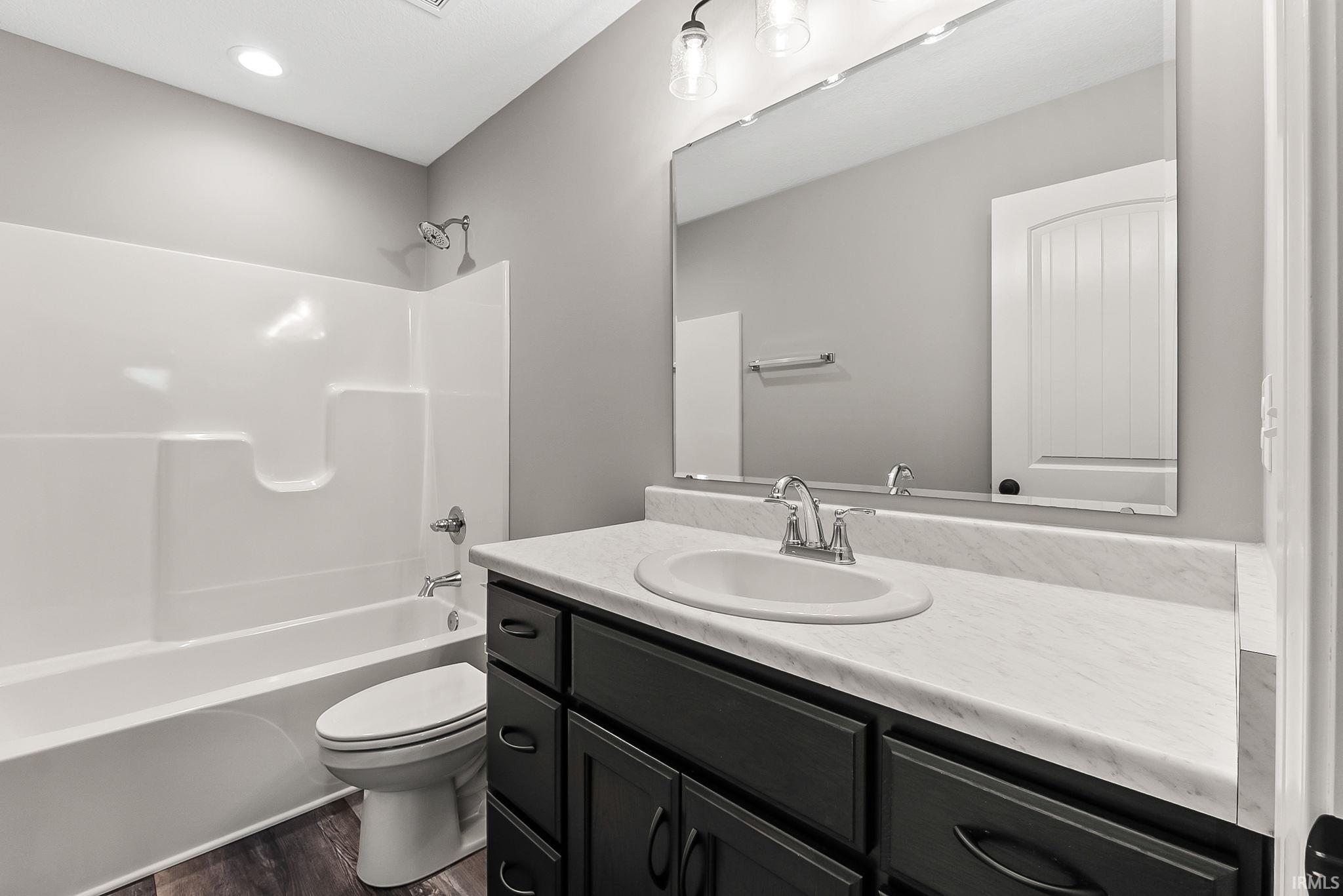 Bathroom with vanity, shower / washtub combination, and dark wood finished floors