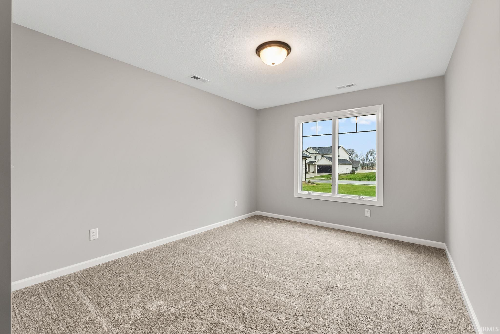Empty room with light carpet and a textured ceiling