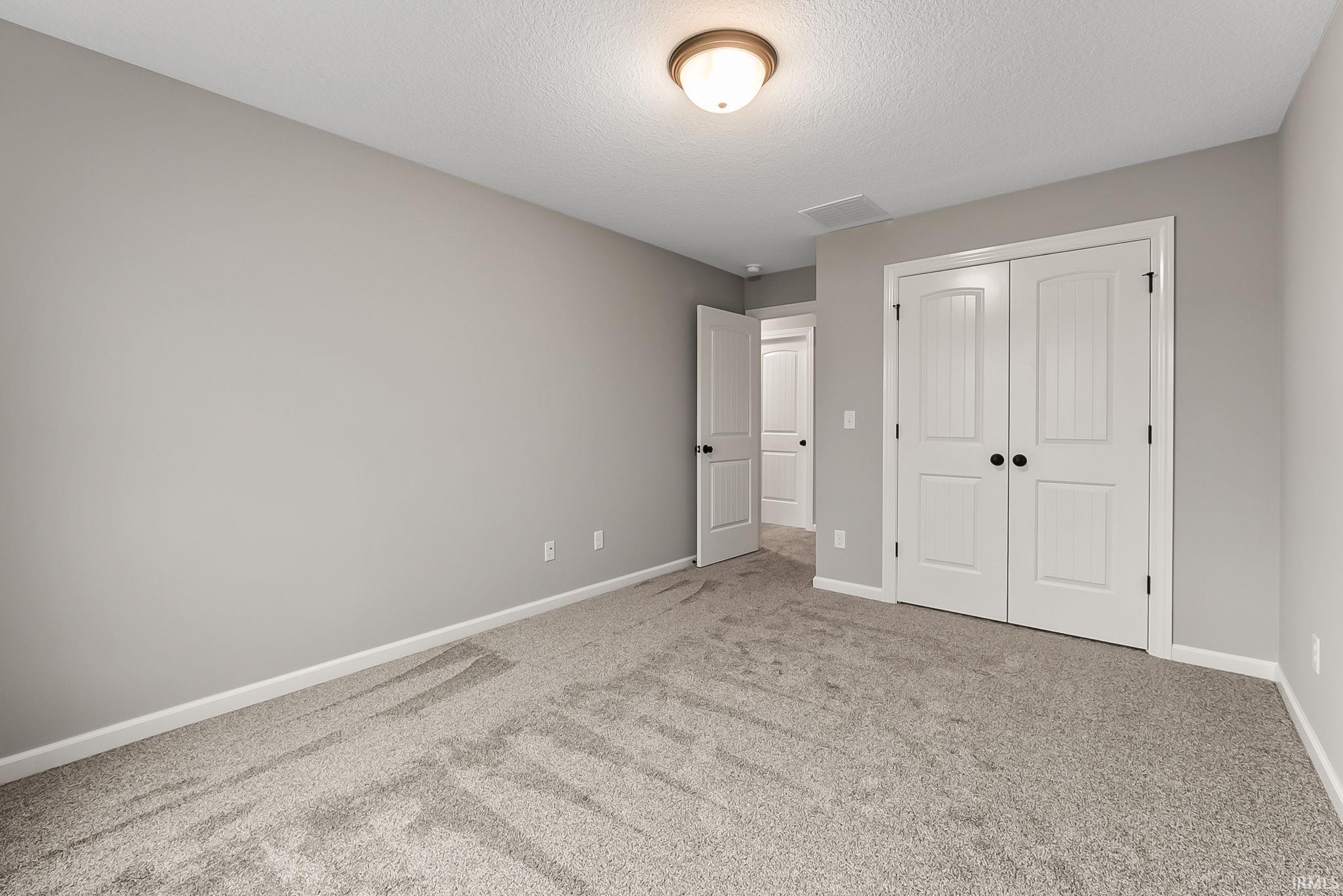 Unfurnished bedroom with light carpet, a closet, and a textured ceiling