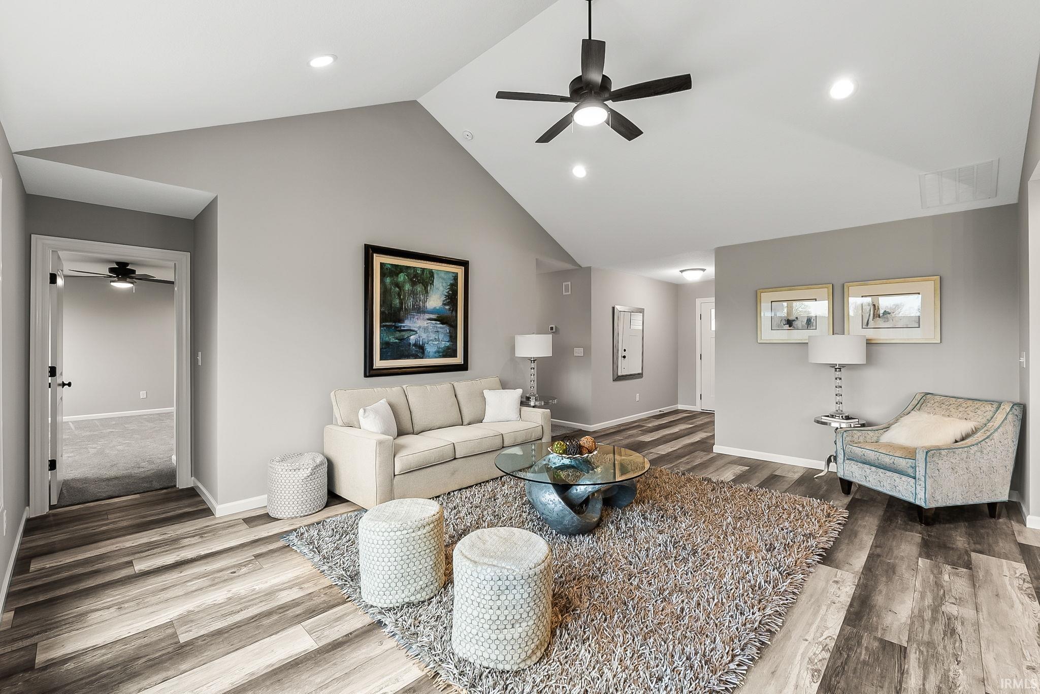 Living area featuring a ceiling fan, wood finished floors, recessed lighting, and a high ceiling