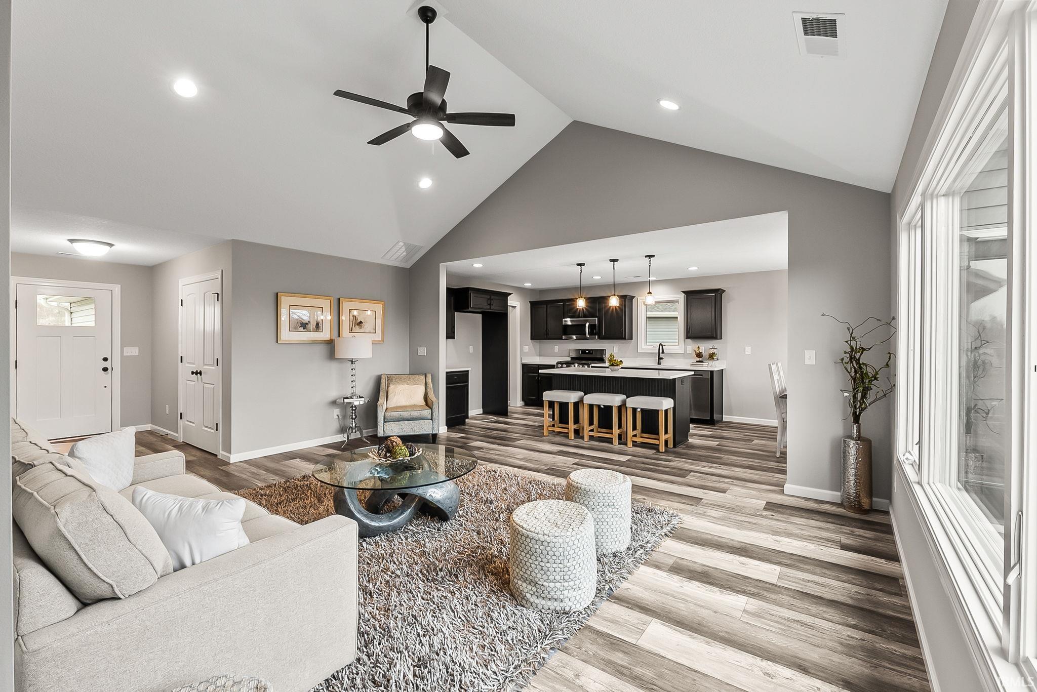Living area featuring ceiling fan, light wood-type flooring, recessed lighting, and a high ceiling
