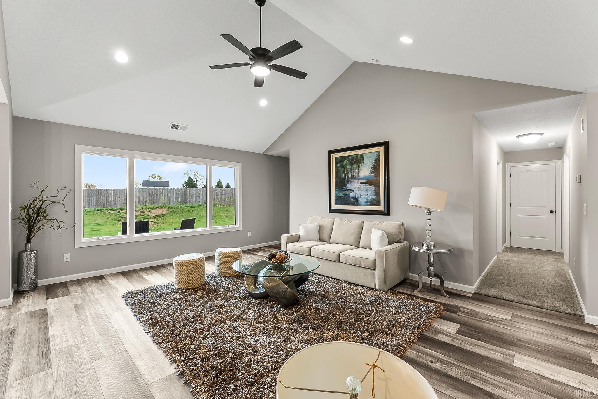 Living room featuring light wood-style floors, ceiling fan, a high ceiling, and recessed lighting
