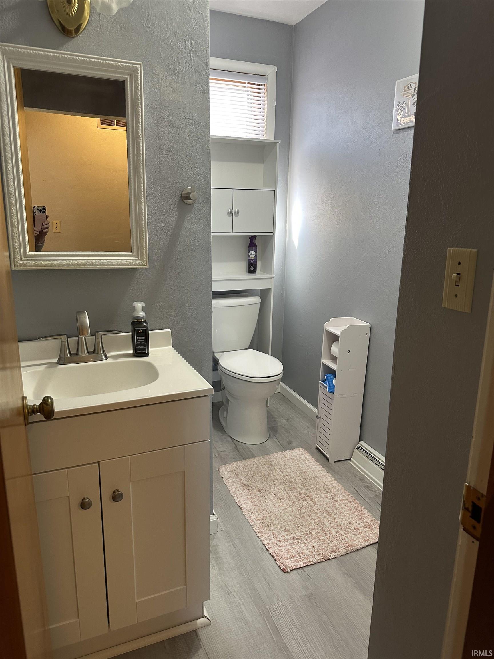 Bathroom featuring vanity, light wood-style flooring, and a textured wall