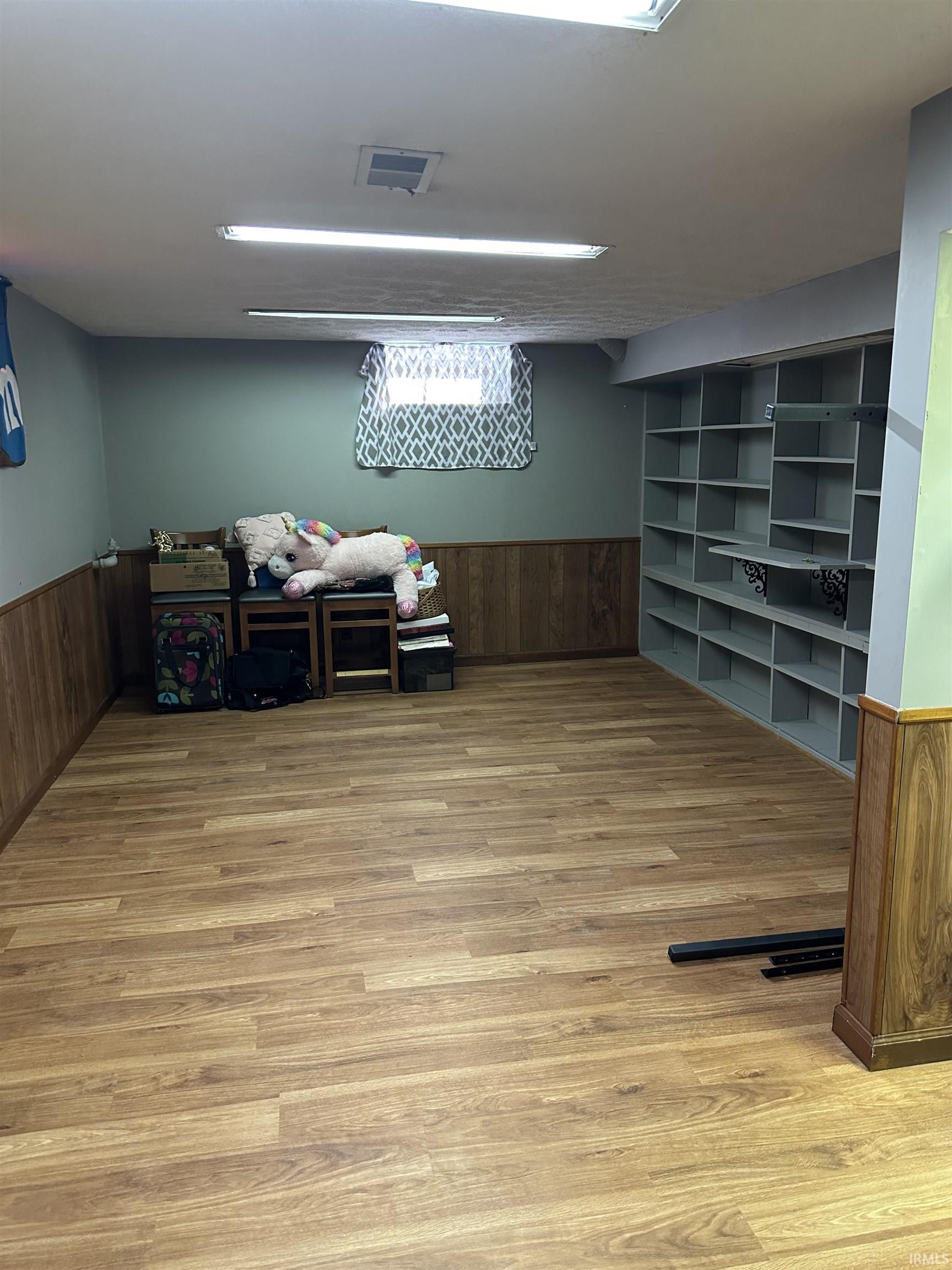 Finished basement with wainscoting, wooden walls, and light wood finished floors