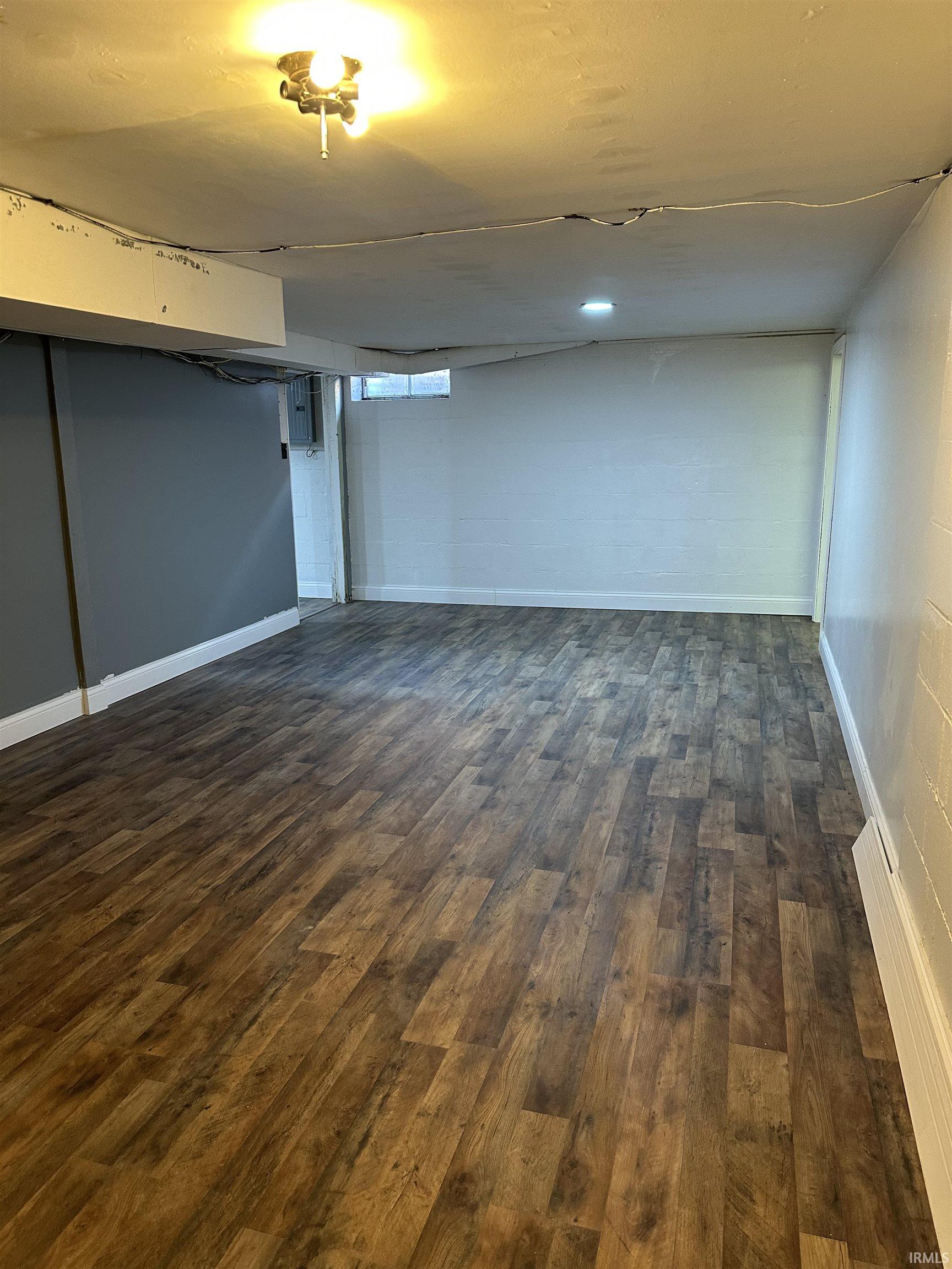 Finished below grade area featuring dark wood-style flooring and electric panel