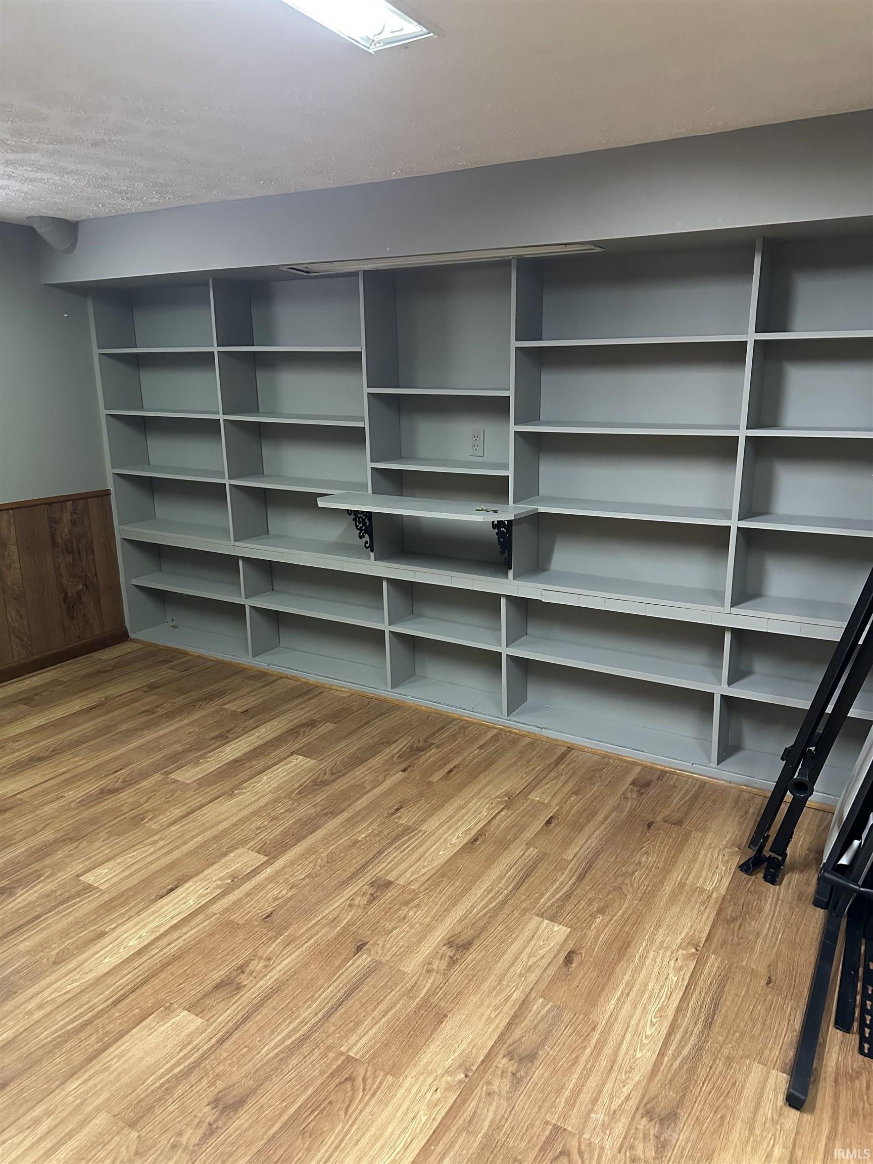 Unfurnished living room featuring light wood-type flooring, a wainscoted wall, and wooden walls