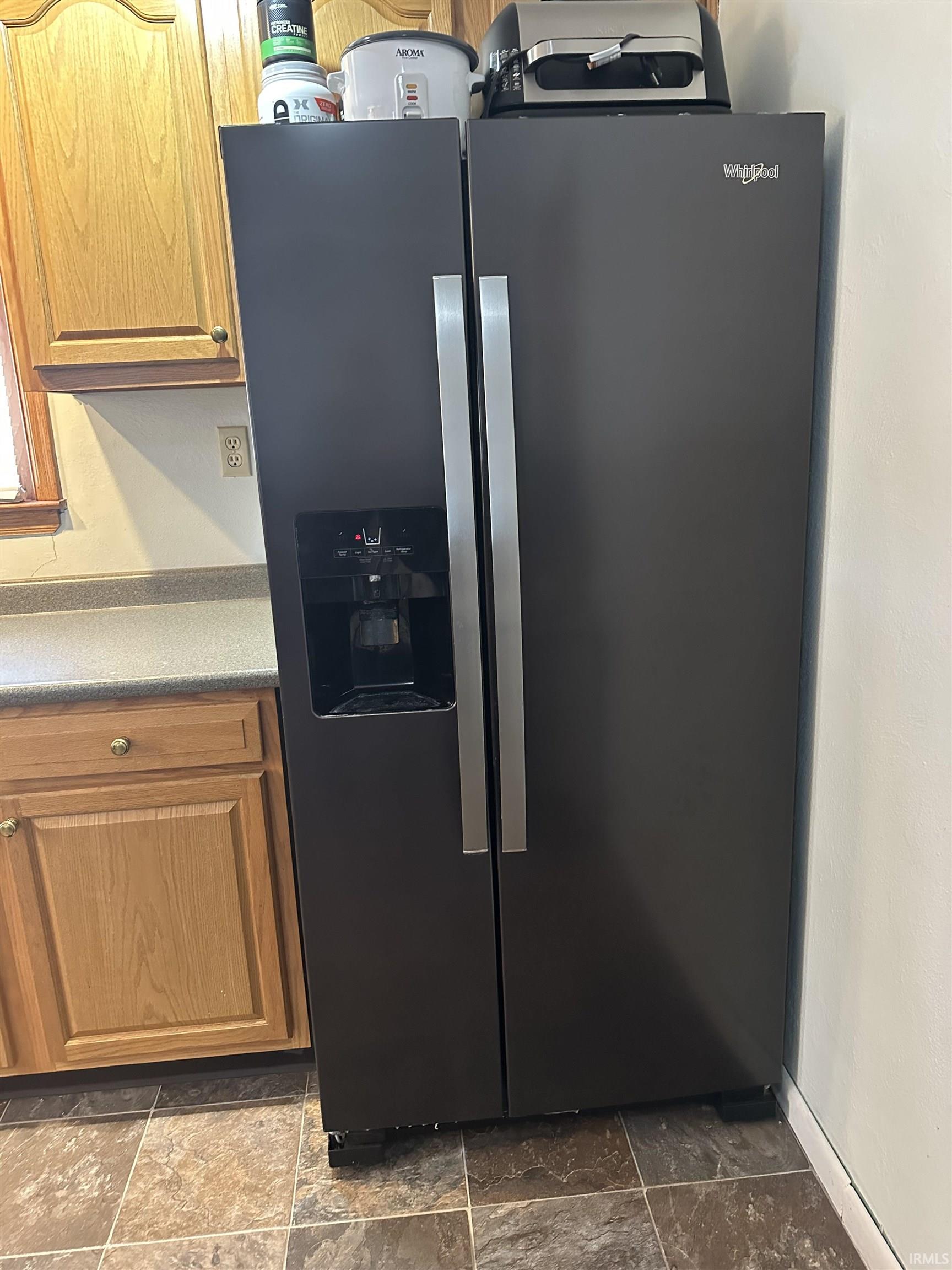 Kitchen view of stainless steel fridge and brown cabinets