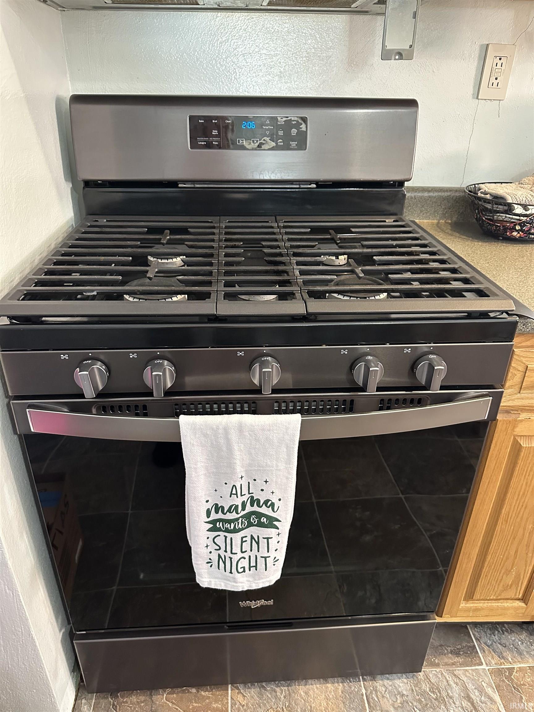 Kitchen view of stainless steel range with gas cooktop and a textured wall