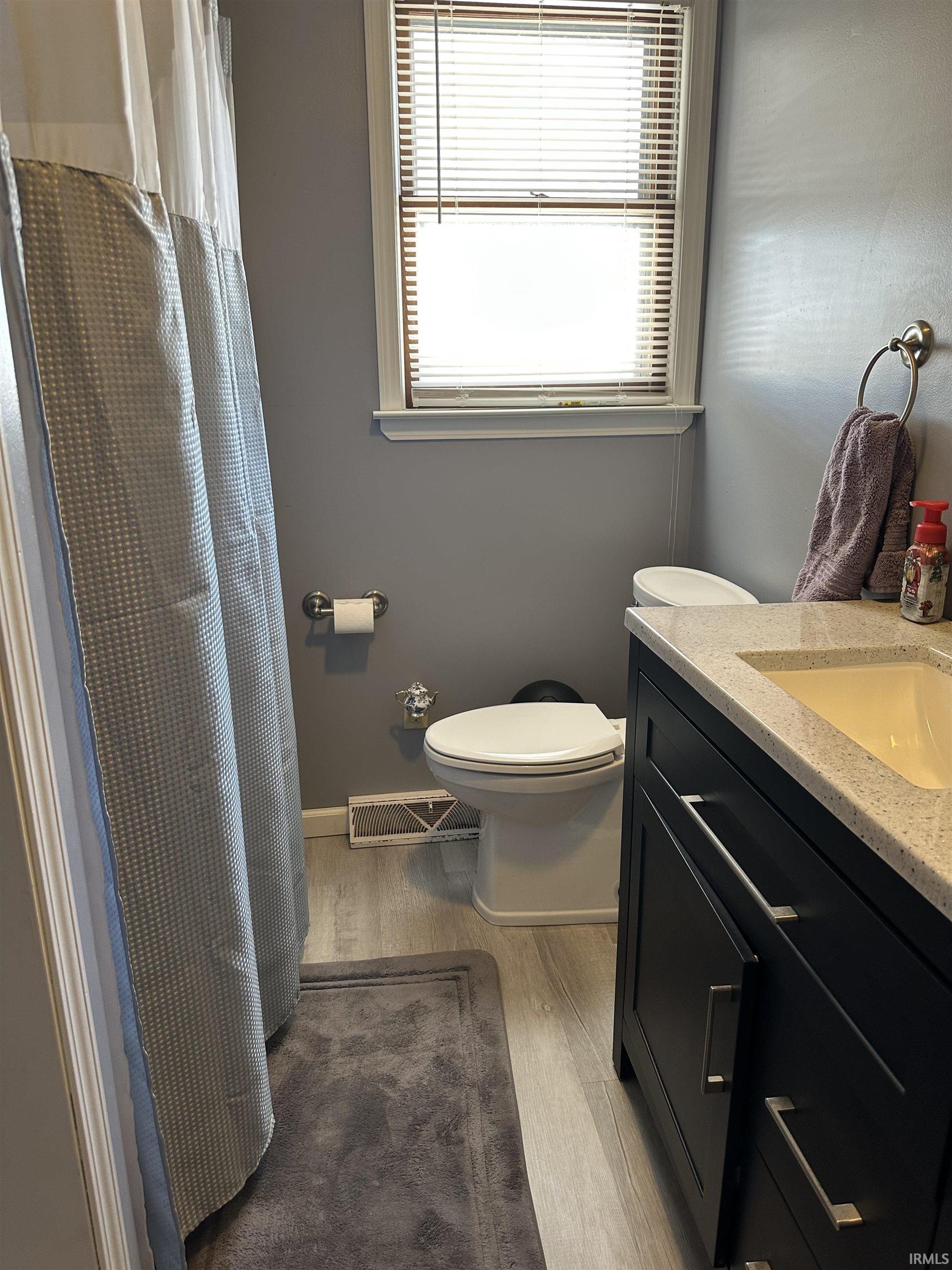 Bathroom with vanity, a shower with shower curtain, and light wood-type flooring