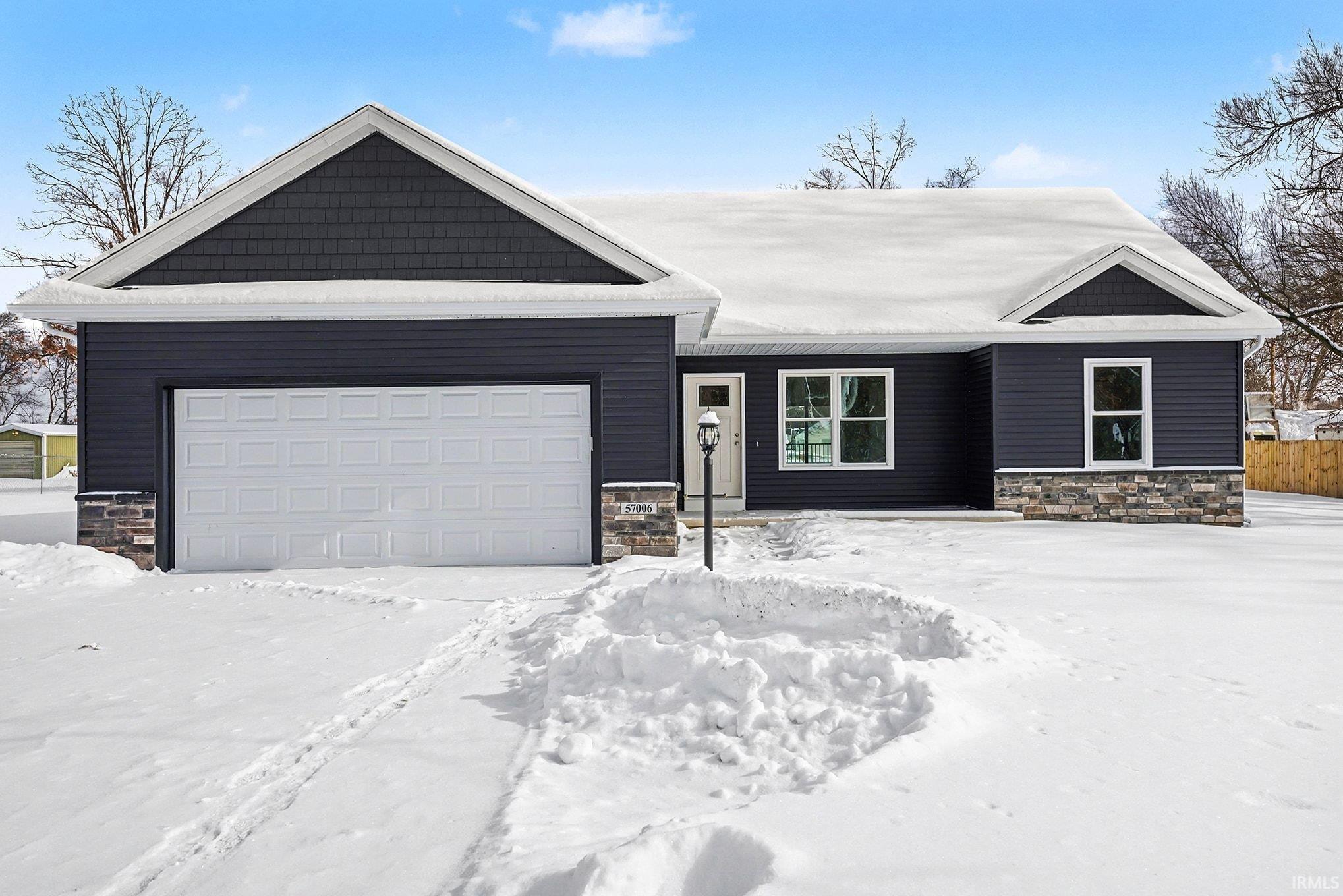 View of front of property with stone siding and a garage
