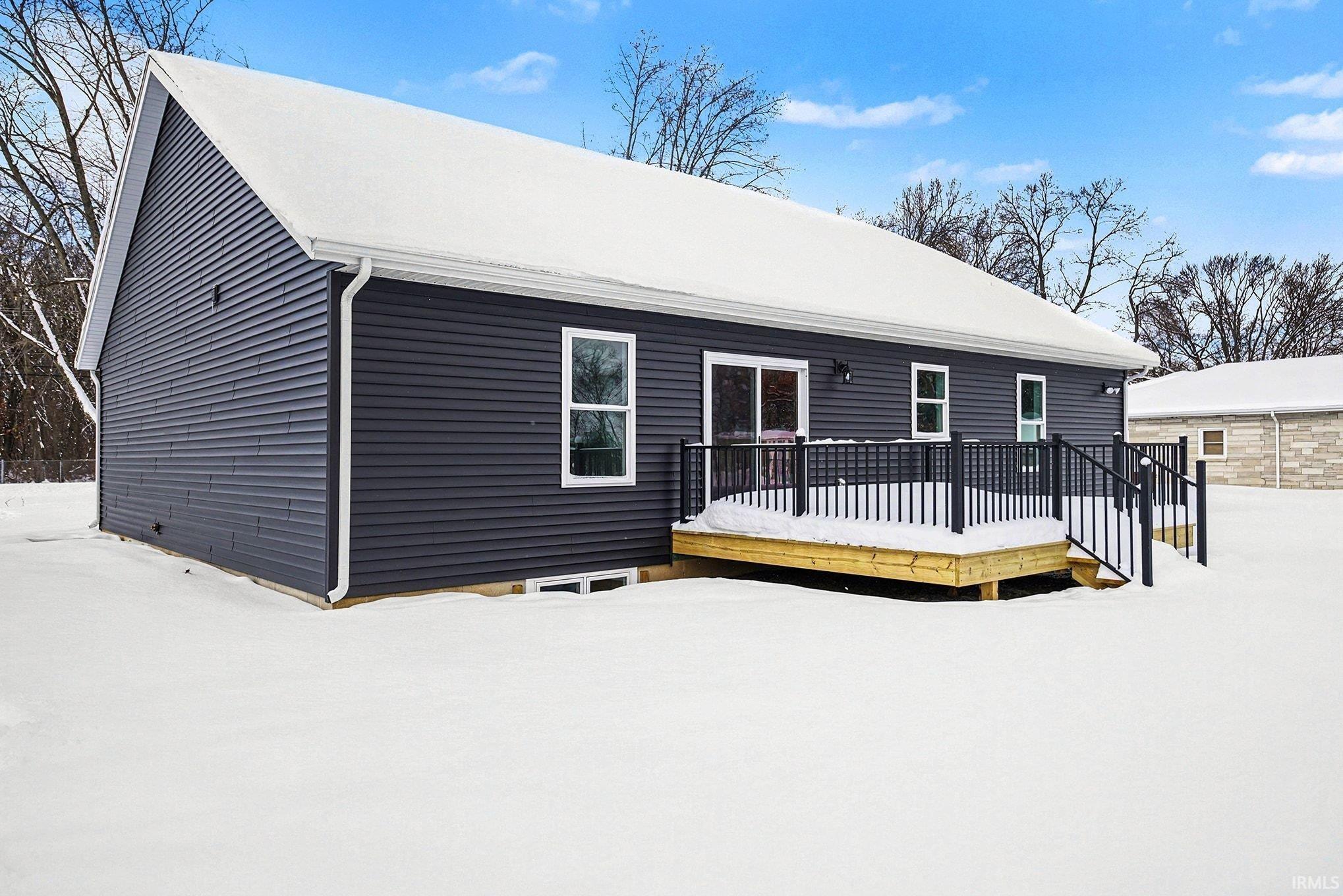 Snow covered house with a wooden deck