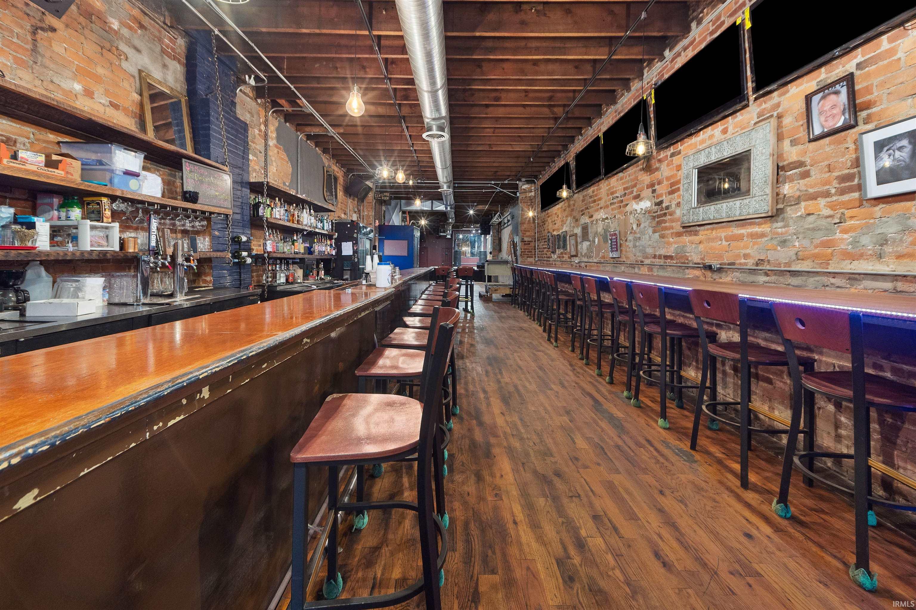 Indoor dry bar featuring brick wall and open shelves