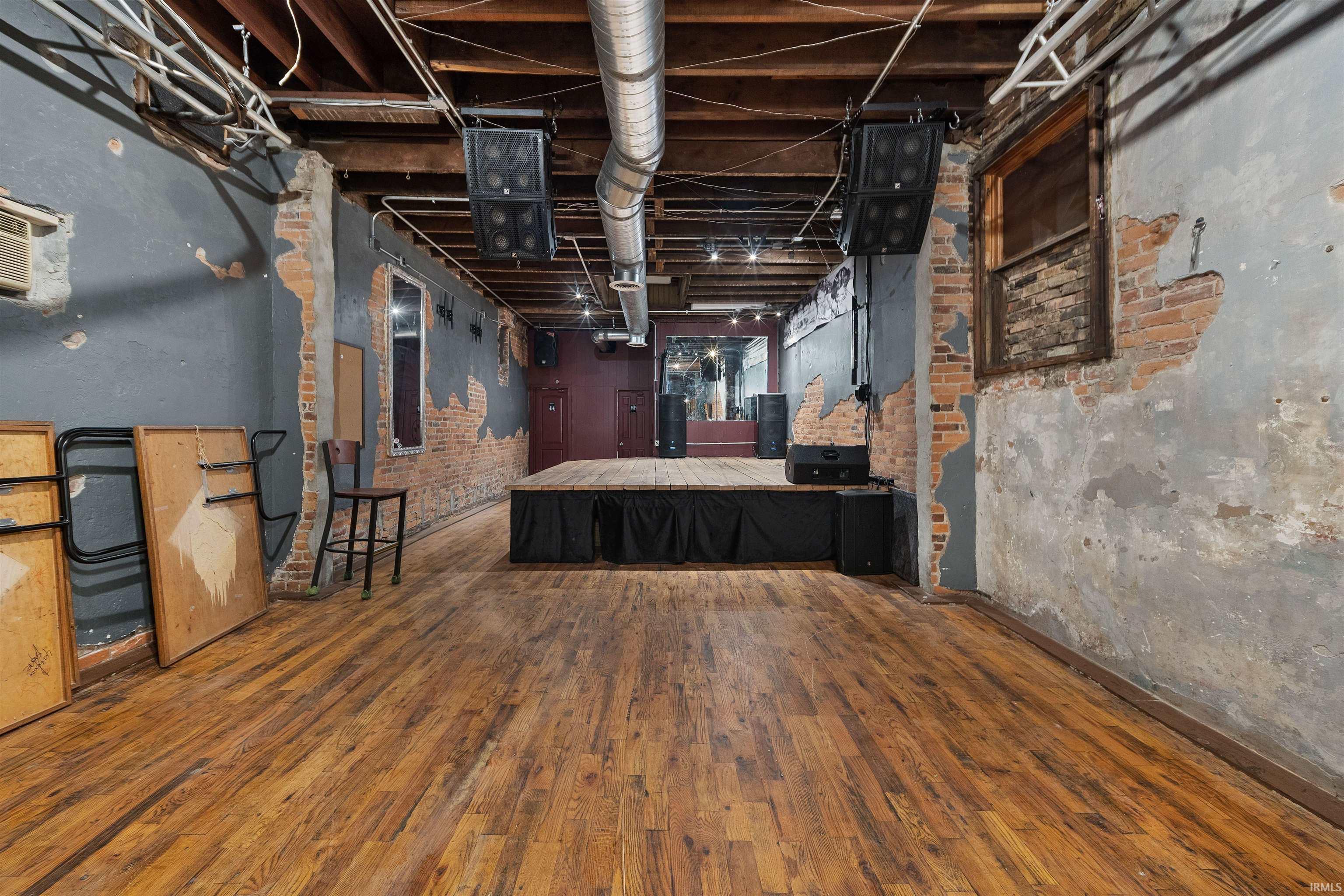 Unfinished below grade area with dark wood finished floors and brick wall