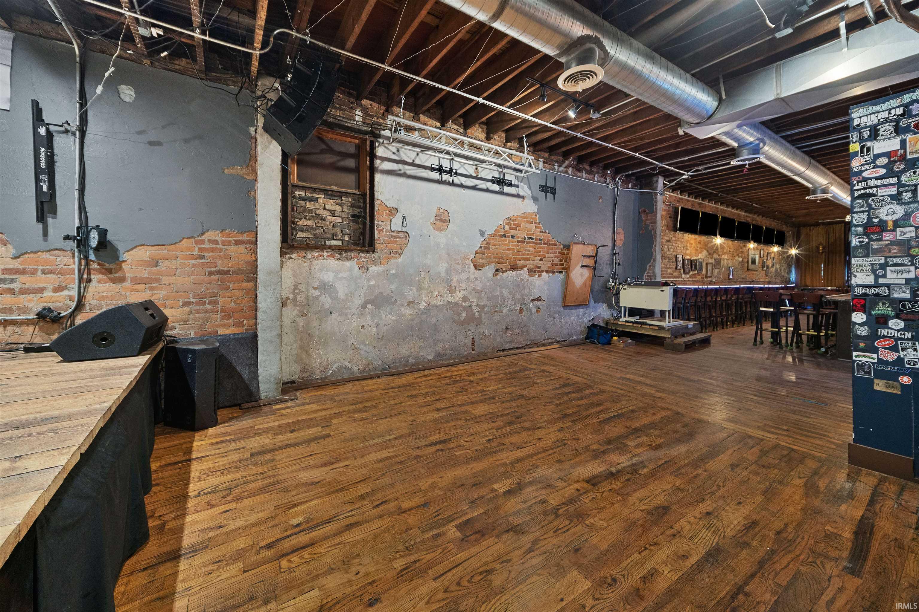 Unfinished basement featuring brick wall and dark wood-style flooring
