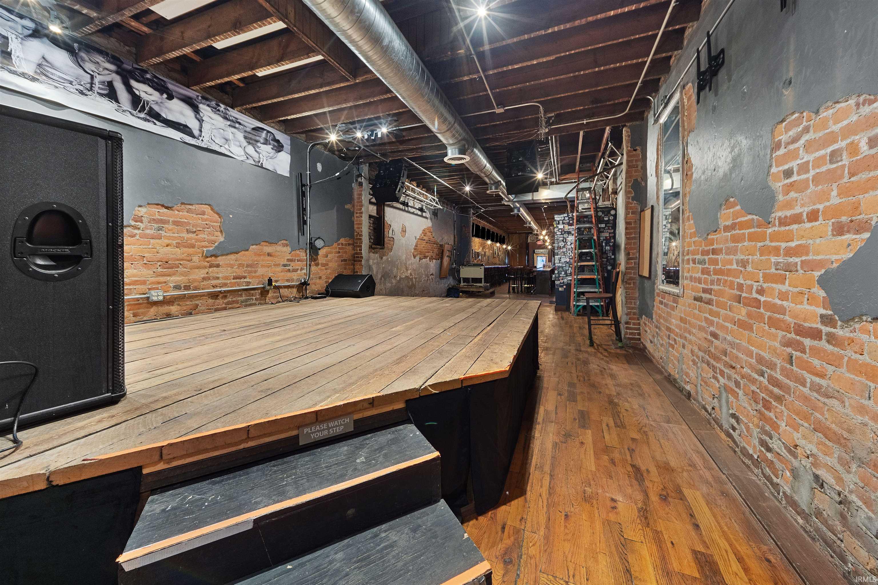 Unfinished below grade area featuring brick wall and dark wood-type flooring