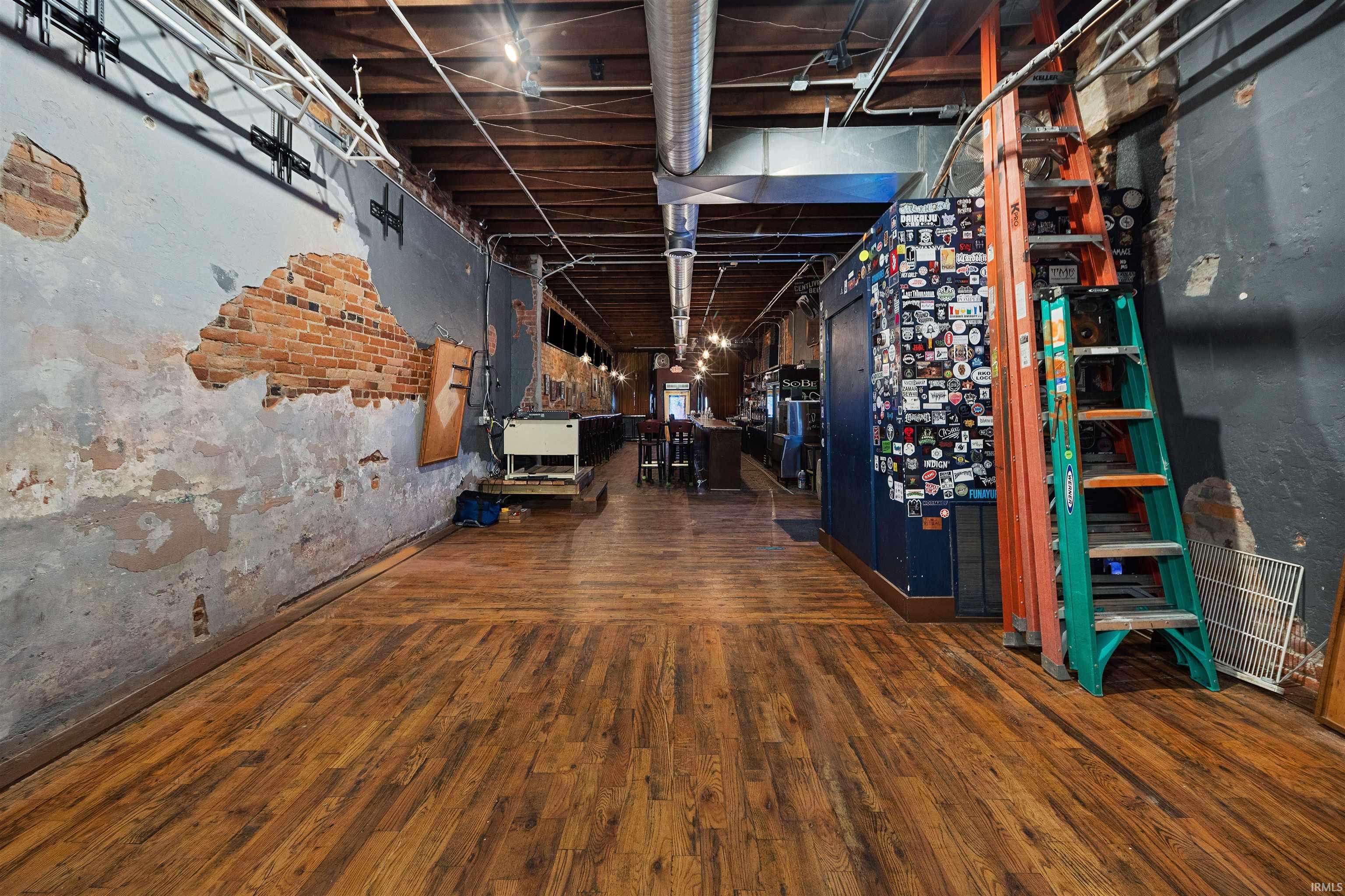 Basement with dark wood-style flooring and a textured wall