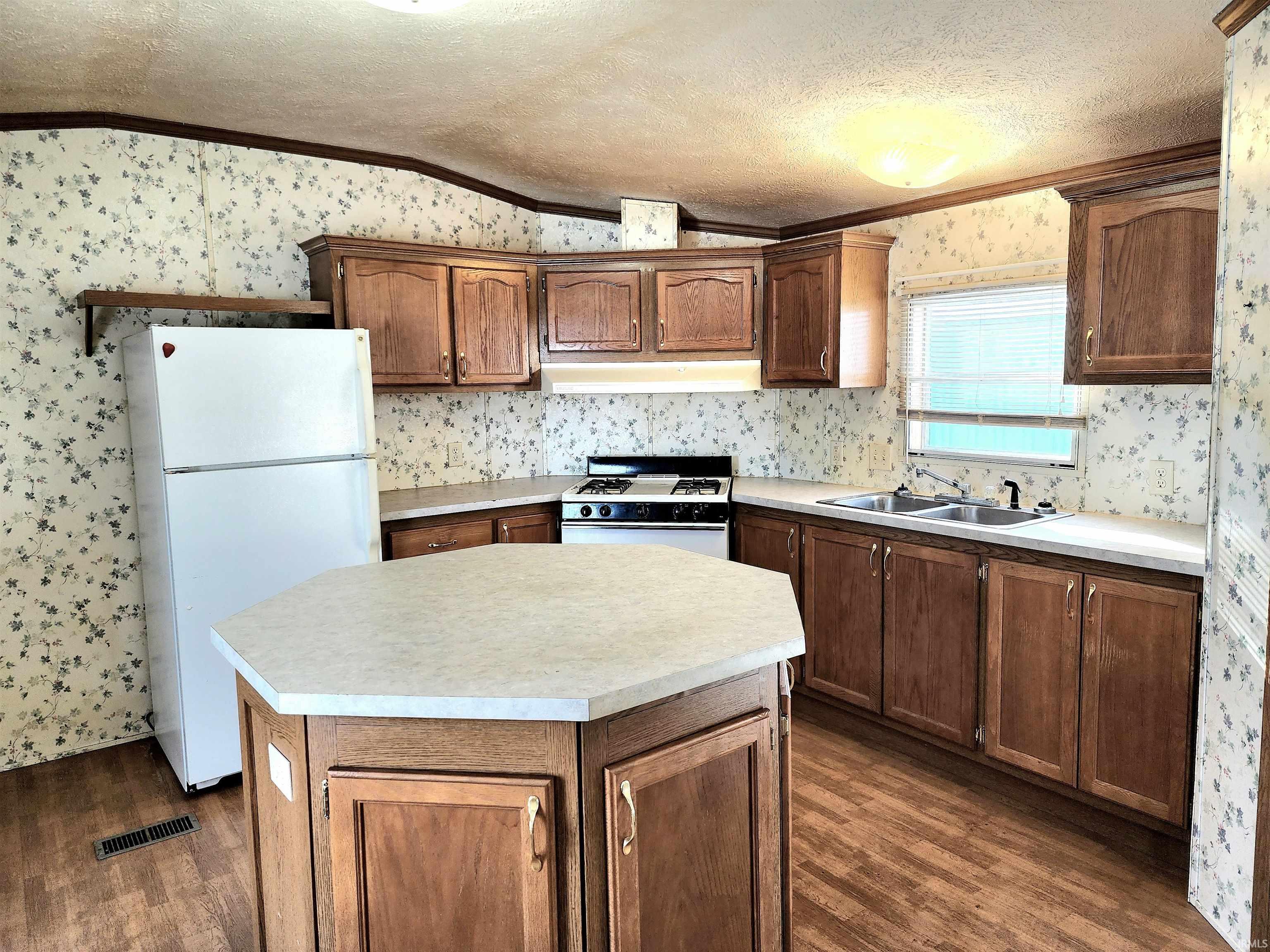 Kitchen featuring a large center island, white appliances, plenty of counter space, an abundance of cabinet storage and crown molding