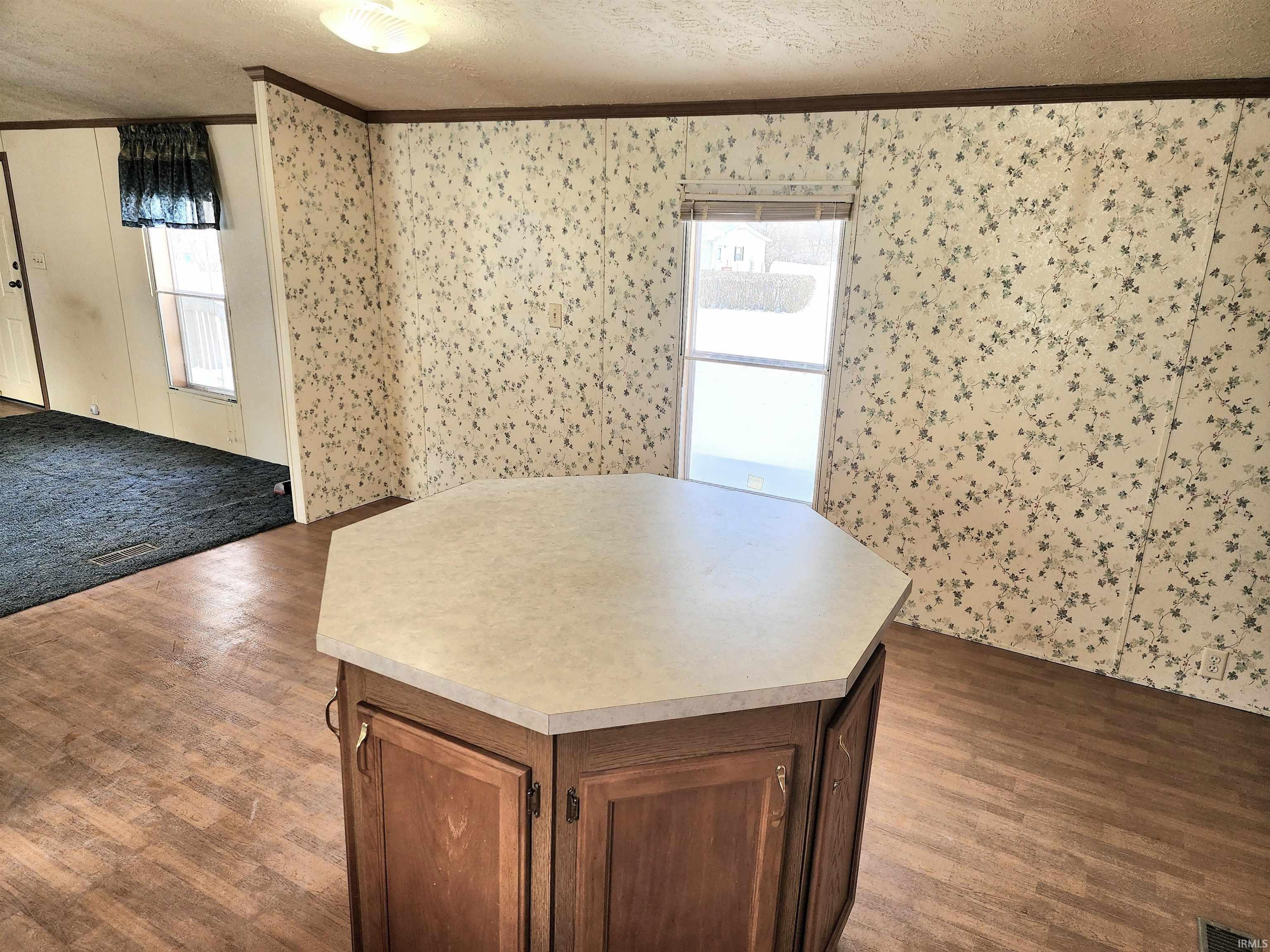 Kitchen featuring a large center island, white appliances, plenty of counter space, an abundance of cabinet storage and crown molding. A space for a dining table is also in the kitchen.