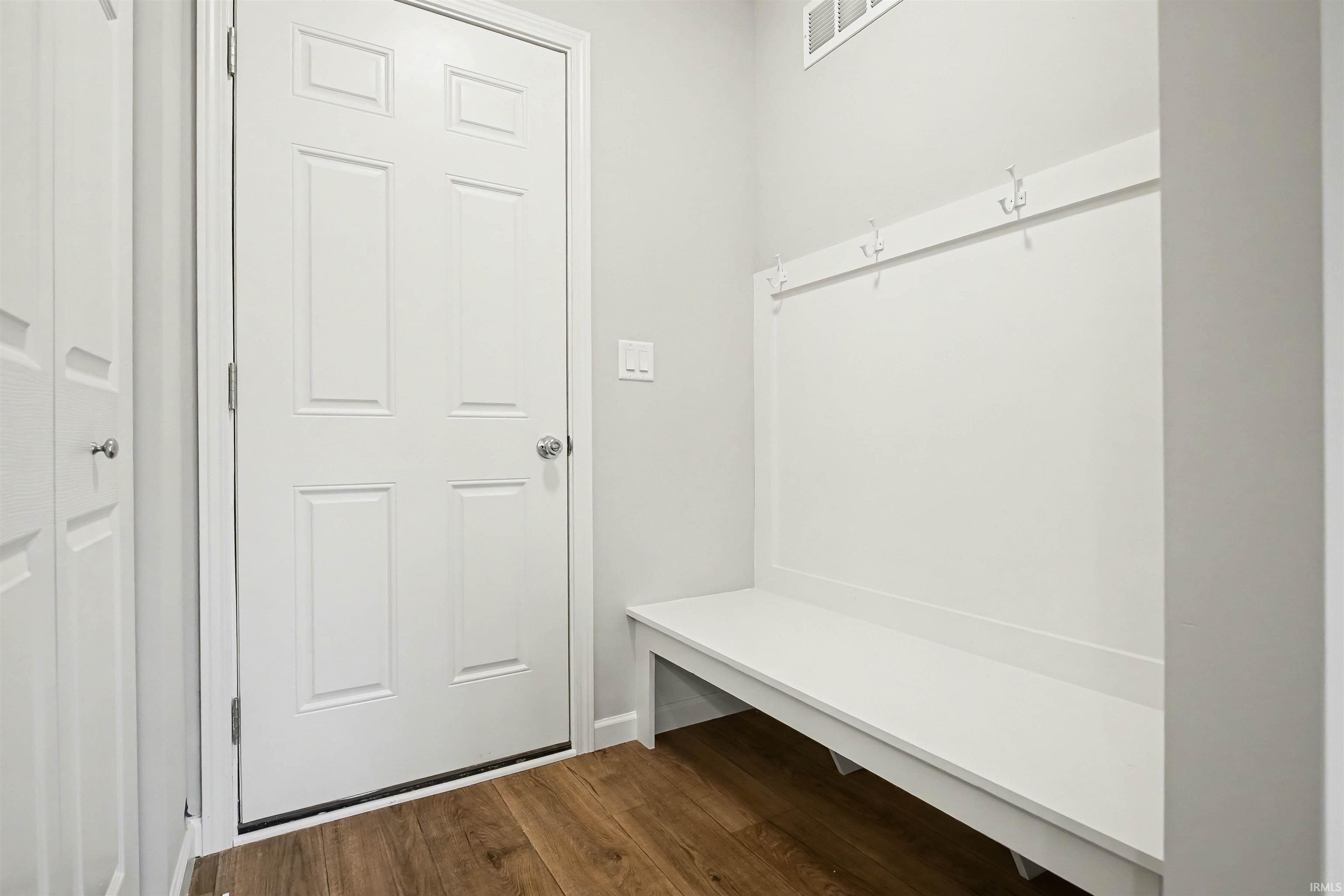 The mudroom has a built-in bench for storage and has access to the garage.