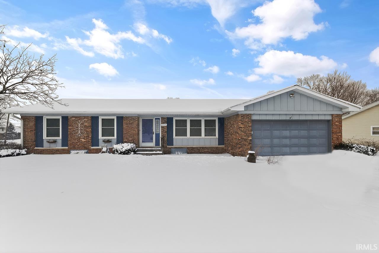 Ranch-style home with board and batten siding, brick siding, and a garage