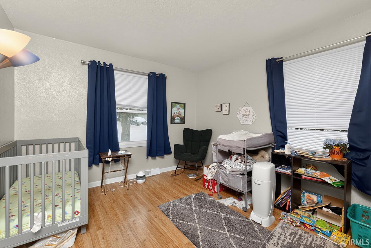 Bedroom with light wood-type flooring and a nursery area
