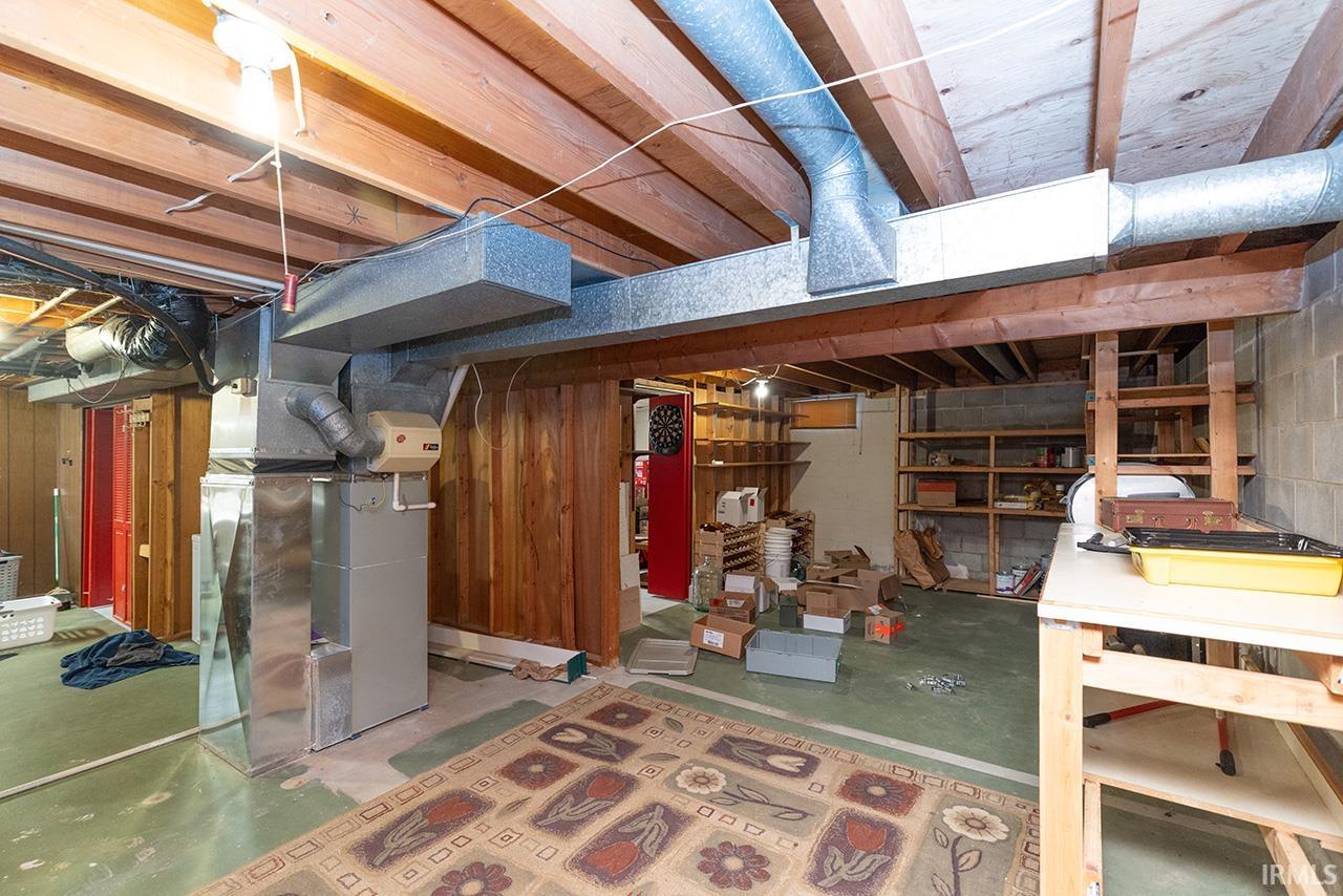 Unfinished basement featuring heating unit and wood walls