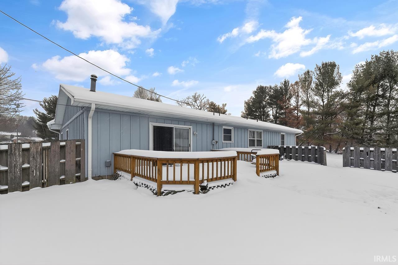Snow covered property with board and batten siding and a deck