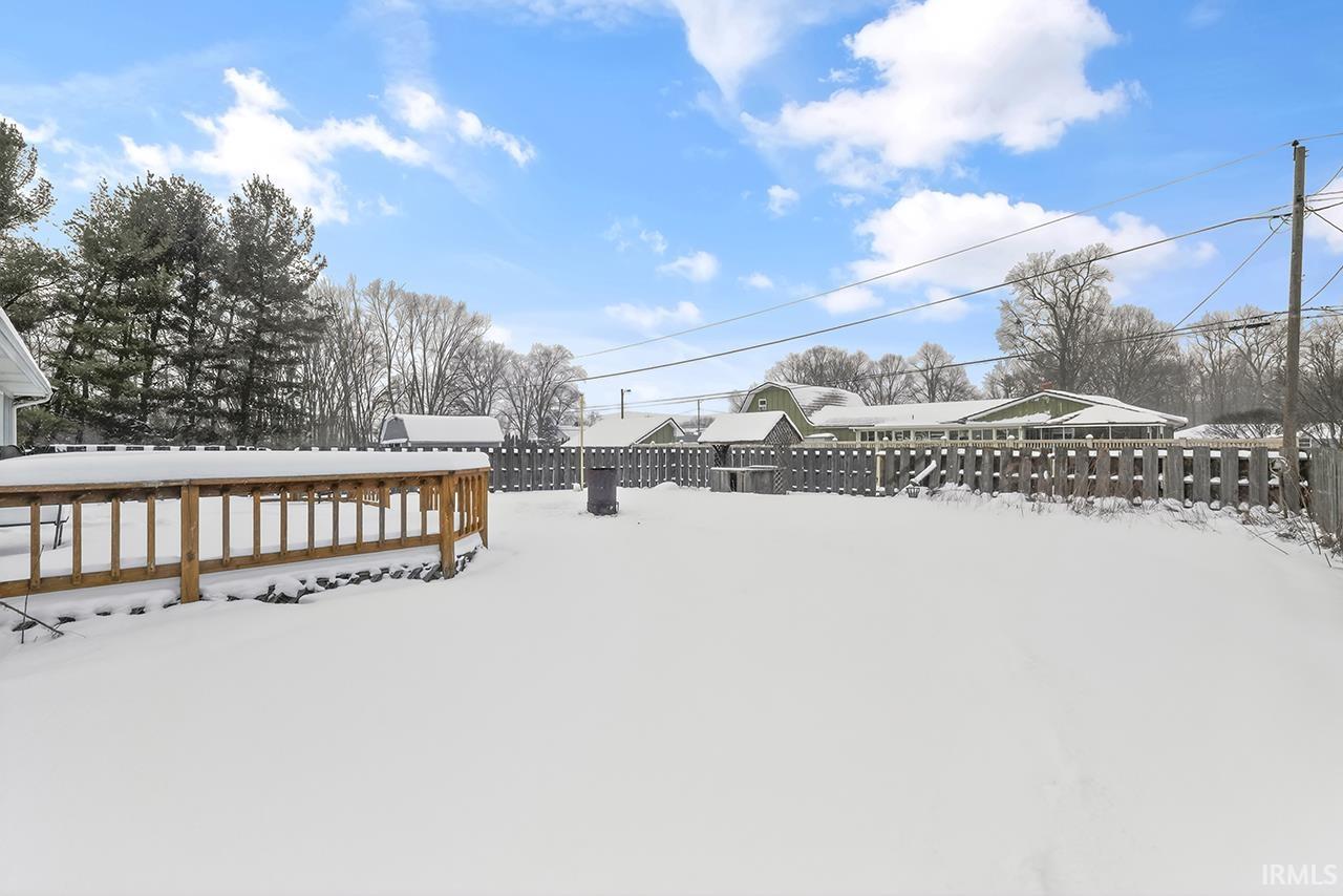 Yard covered in snow with a fenced backyard and a deck