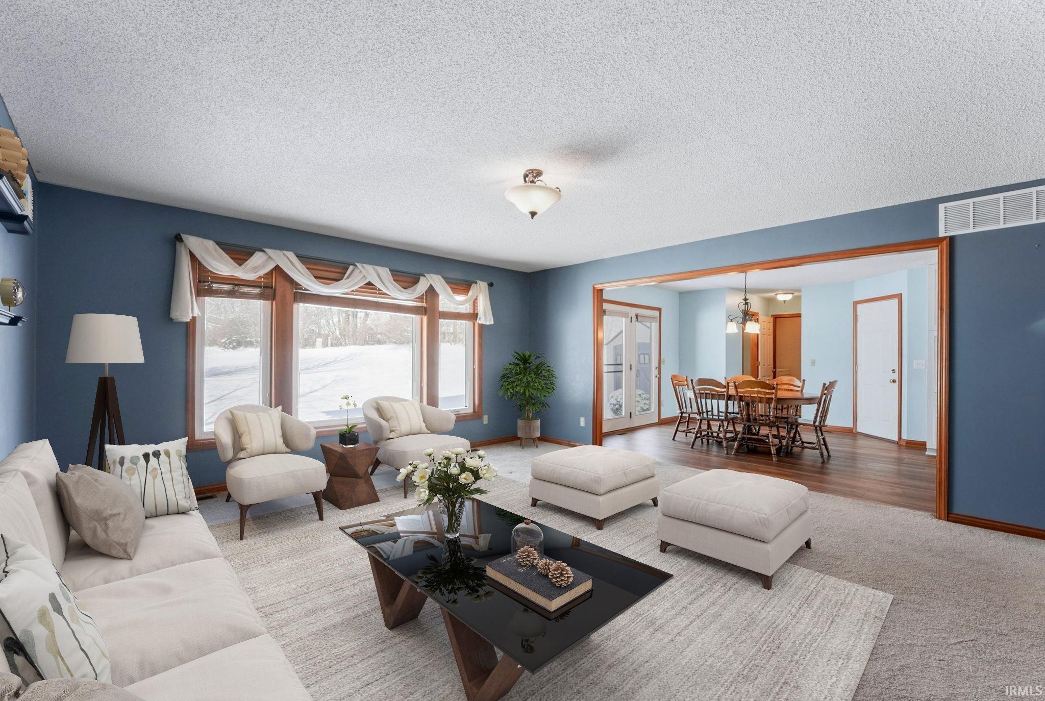Living area featuring carpet floors, a textured ceiling, and a chandelier