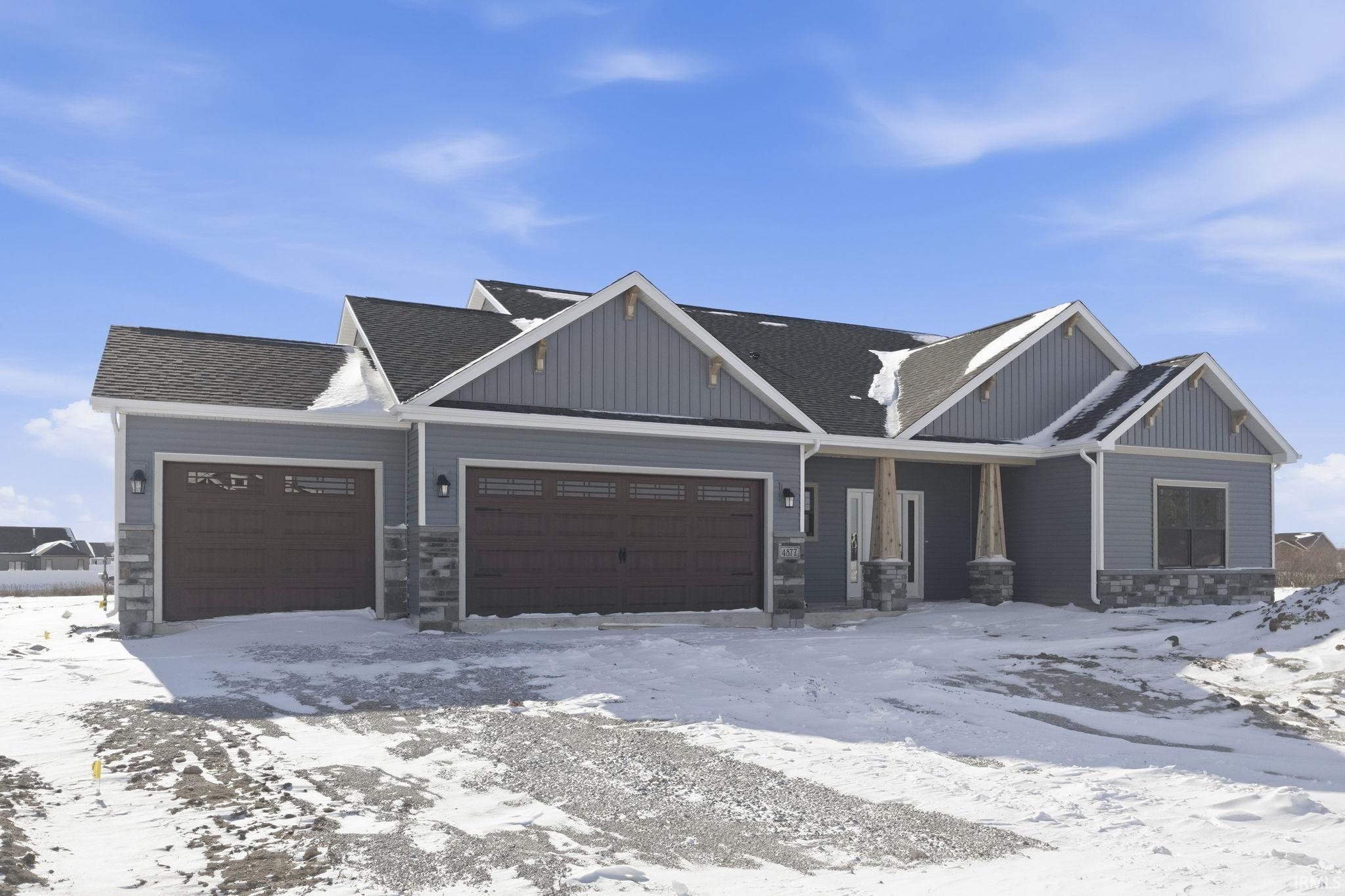 Craftsman-style house featuring stone siding, a garage, roof with shingles, covered porch, and board and batten siding