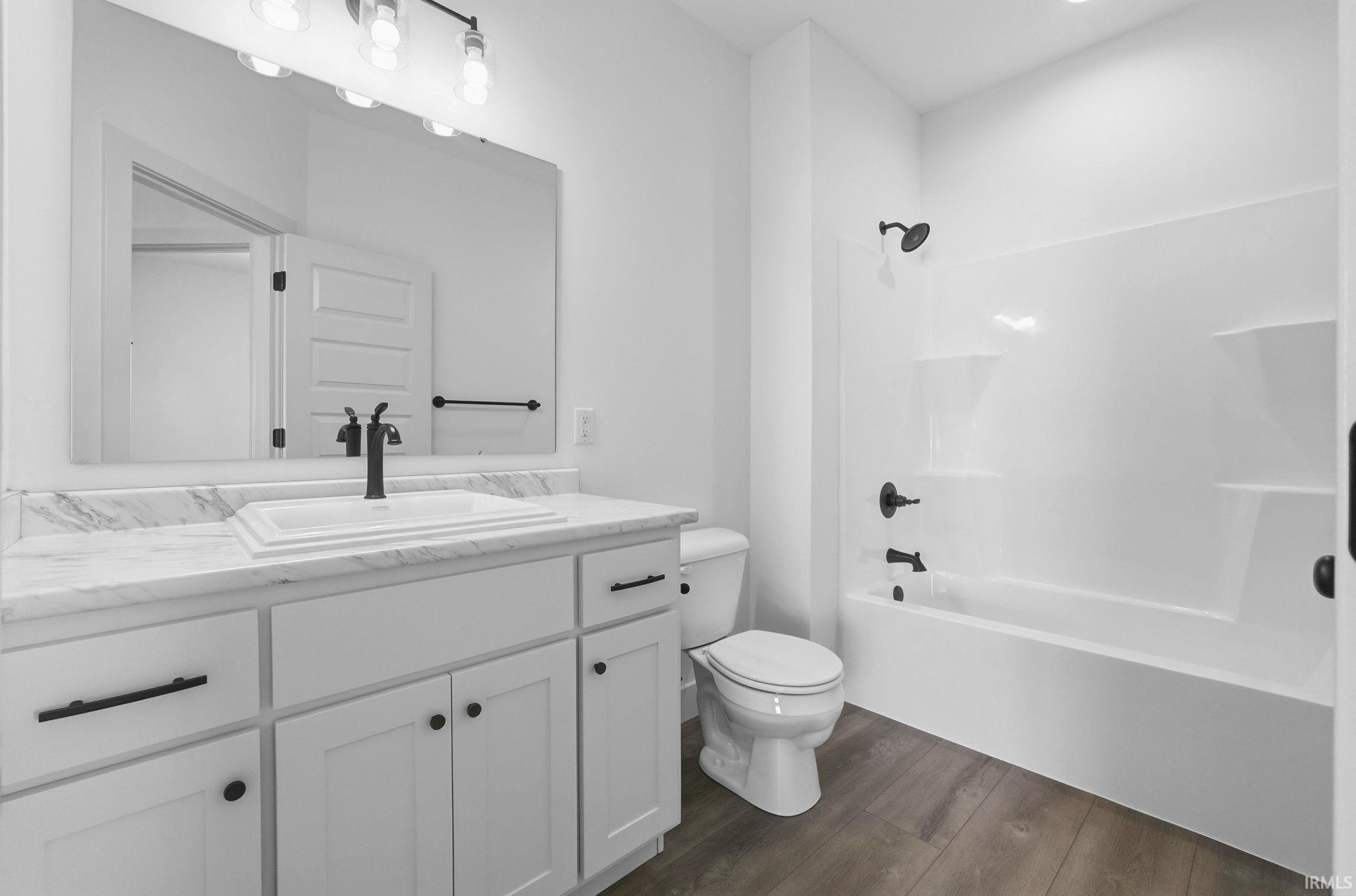 Bathroom featuring  shower combination, vanity, and dark wood-type flooring