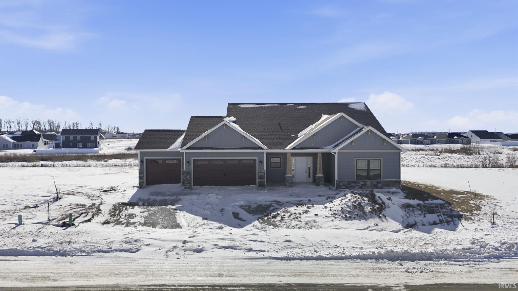 View of front of home featuring a garage and stone siding