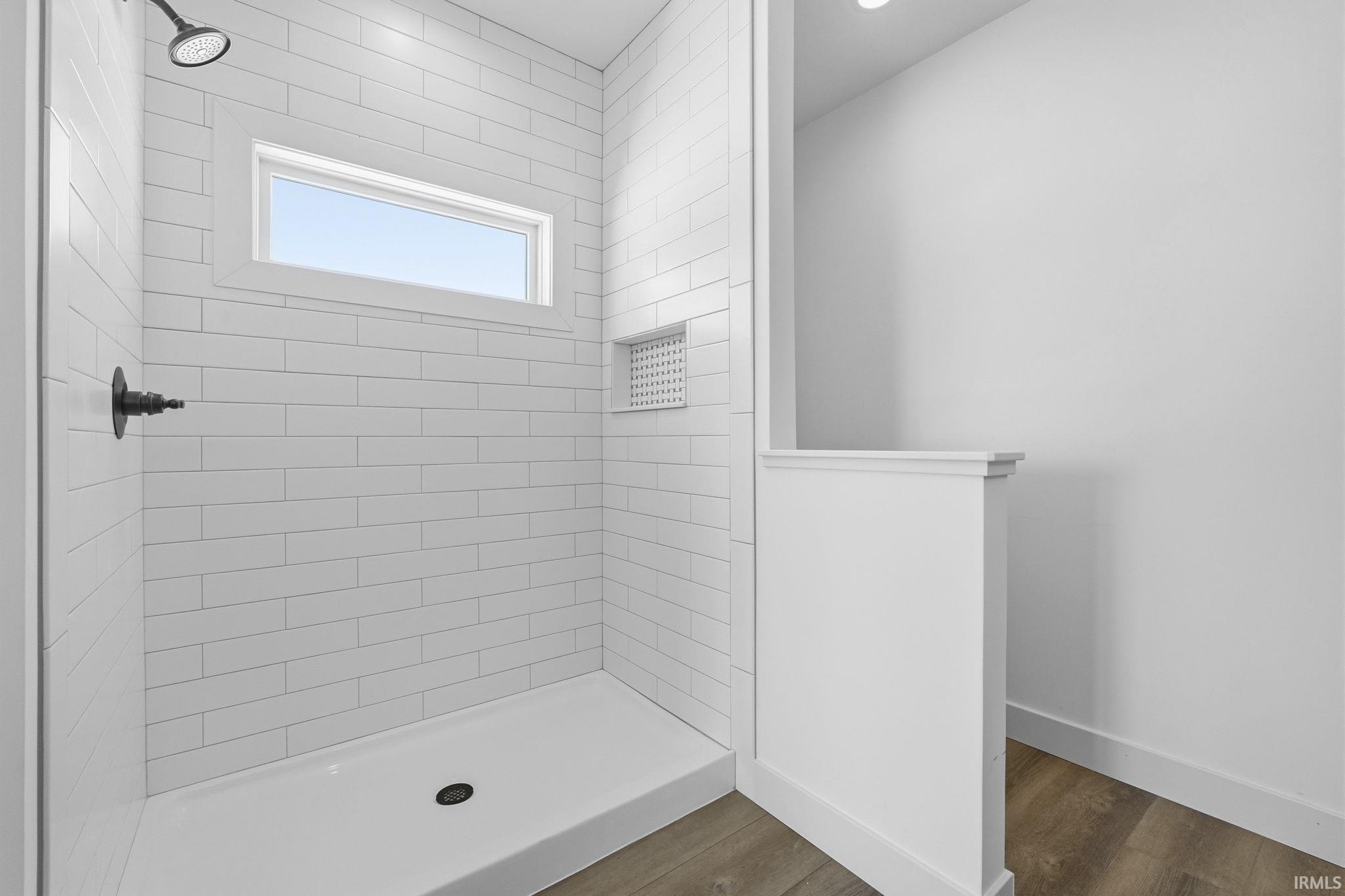 Full bathroom with a tile shower and dark wood-style floors