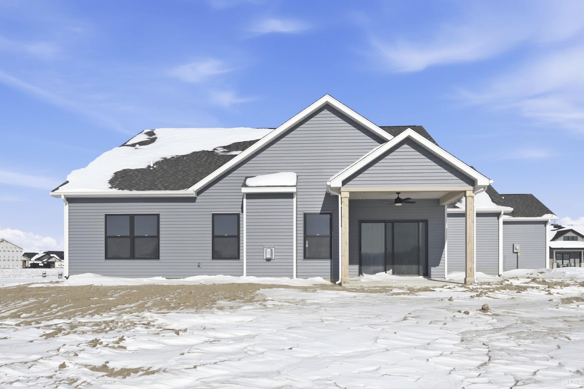 View of front of property with a patio, ceiling fan, and a shingled roof