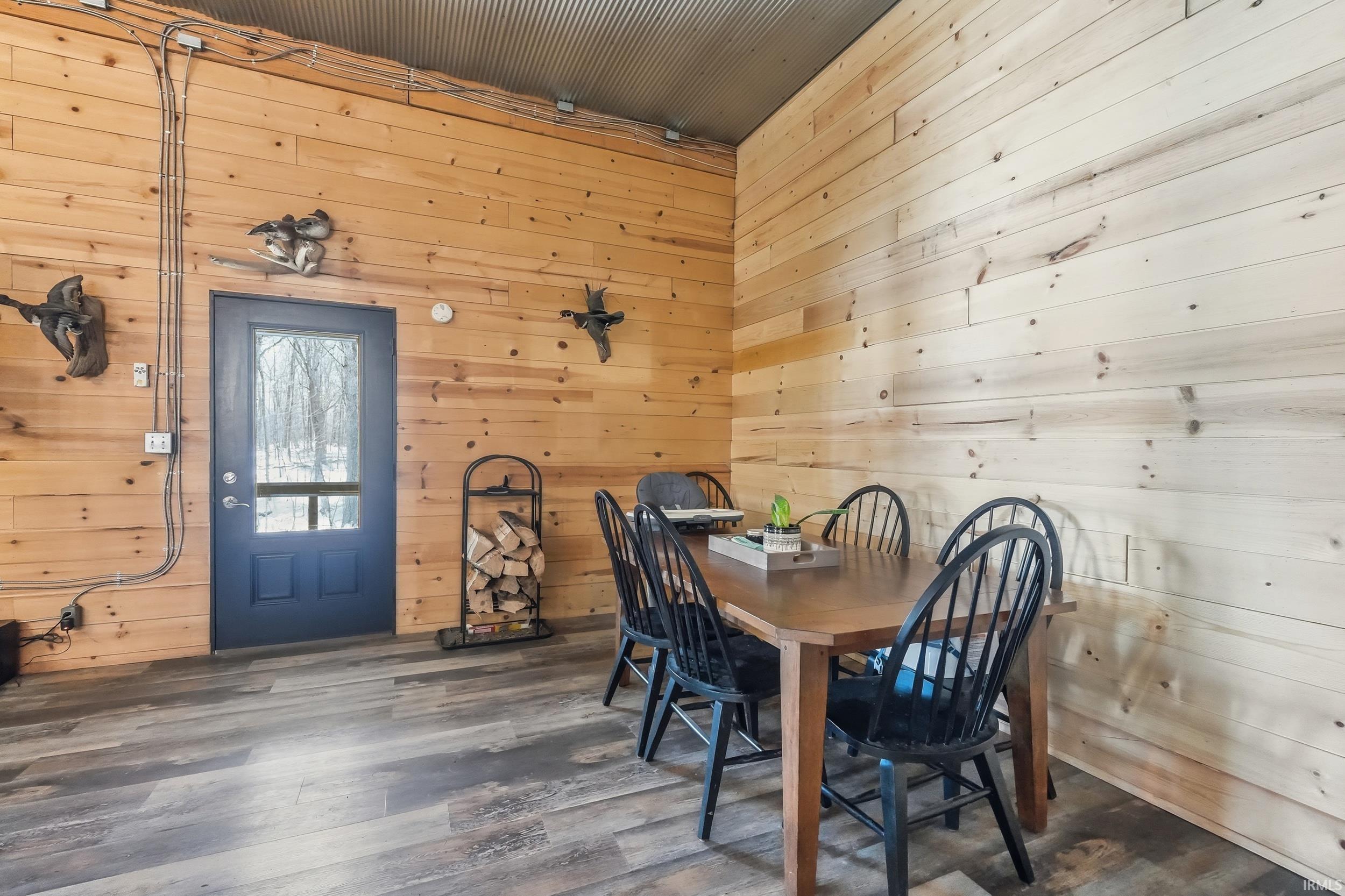 Dining area with wooden walls and wood finished floors