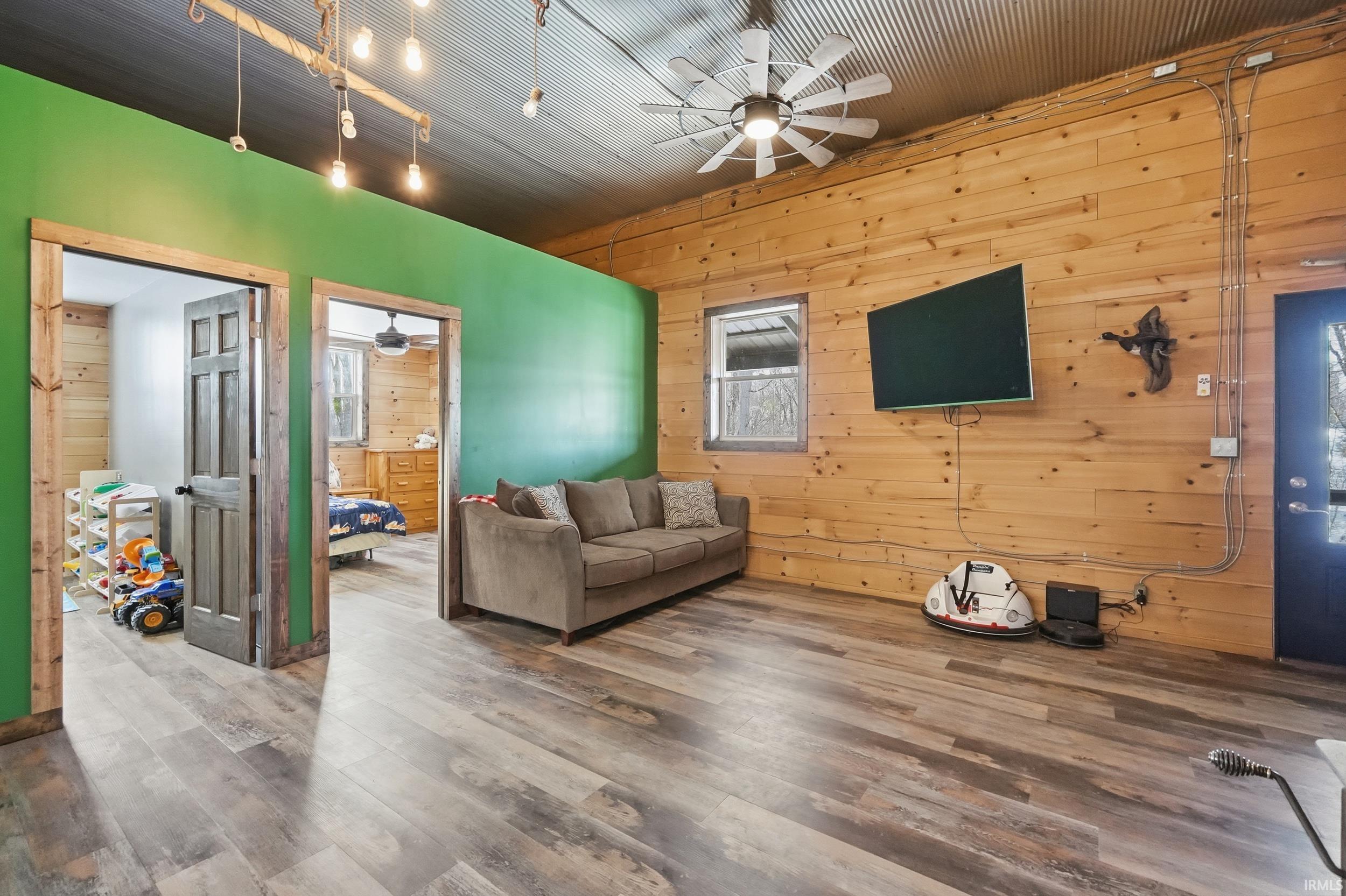 Living area with wooden walls, ceiling fan, and wood finished floors