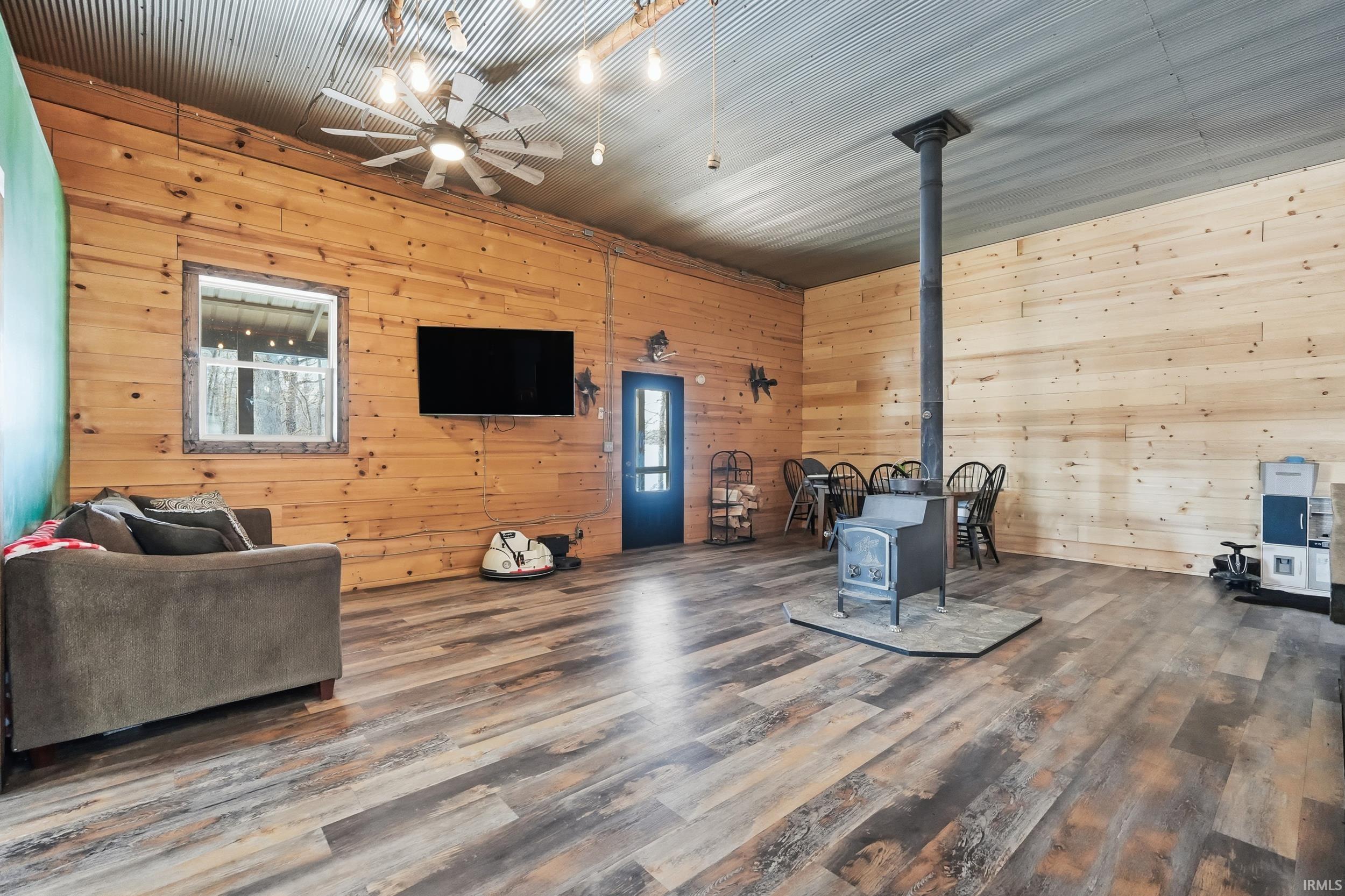 Living room featuring a wood stove, wooden walls, and wood finished floors