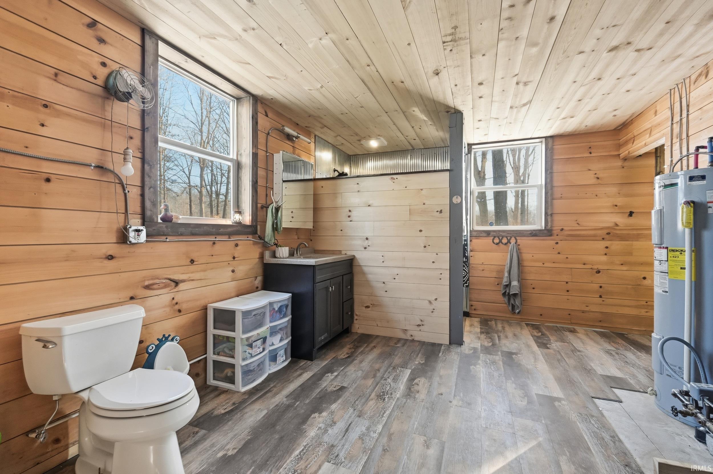Bathroom with wood walls, vanity, water heater, hardwood / wood-style flooring, and plenty of natural light
