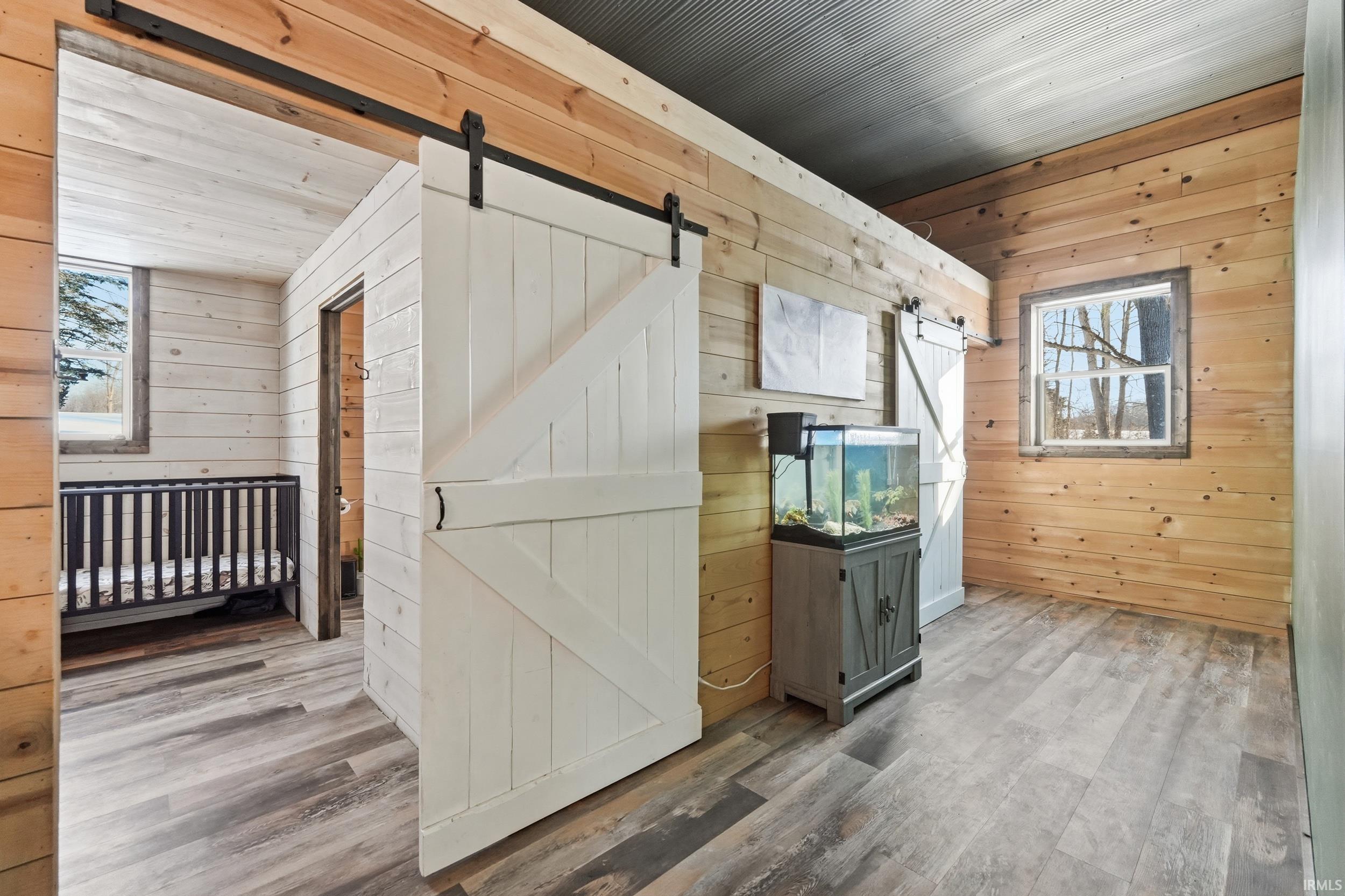 Interior space with wood walls, a barn door, wood finished floors, and wood ceiling