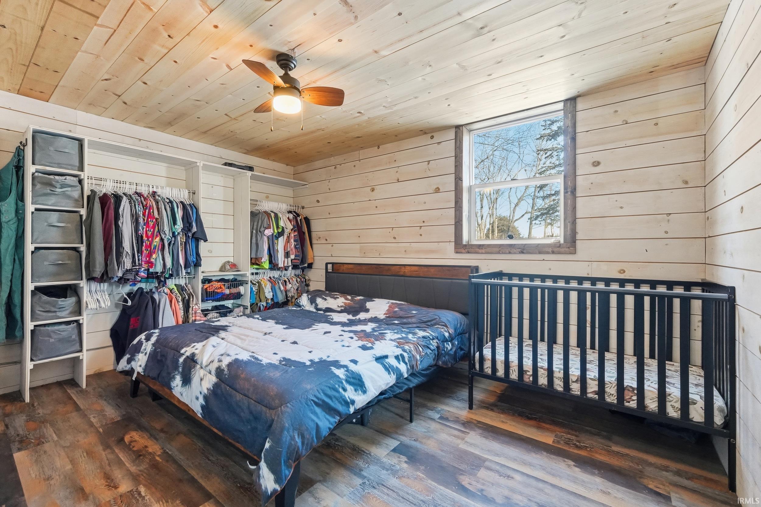 Bedroom with wood walls, wood ceiling, hardwood / wood-style floors, a ceiling fan, and a closet