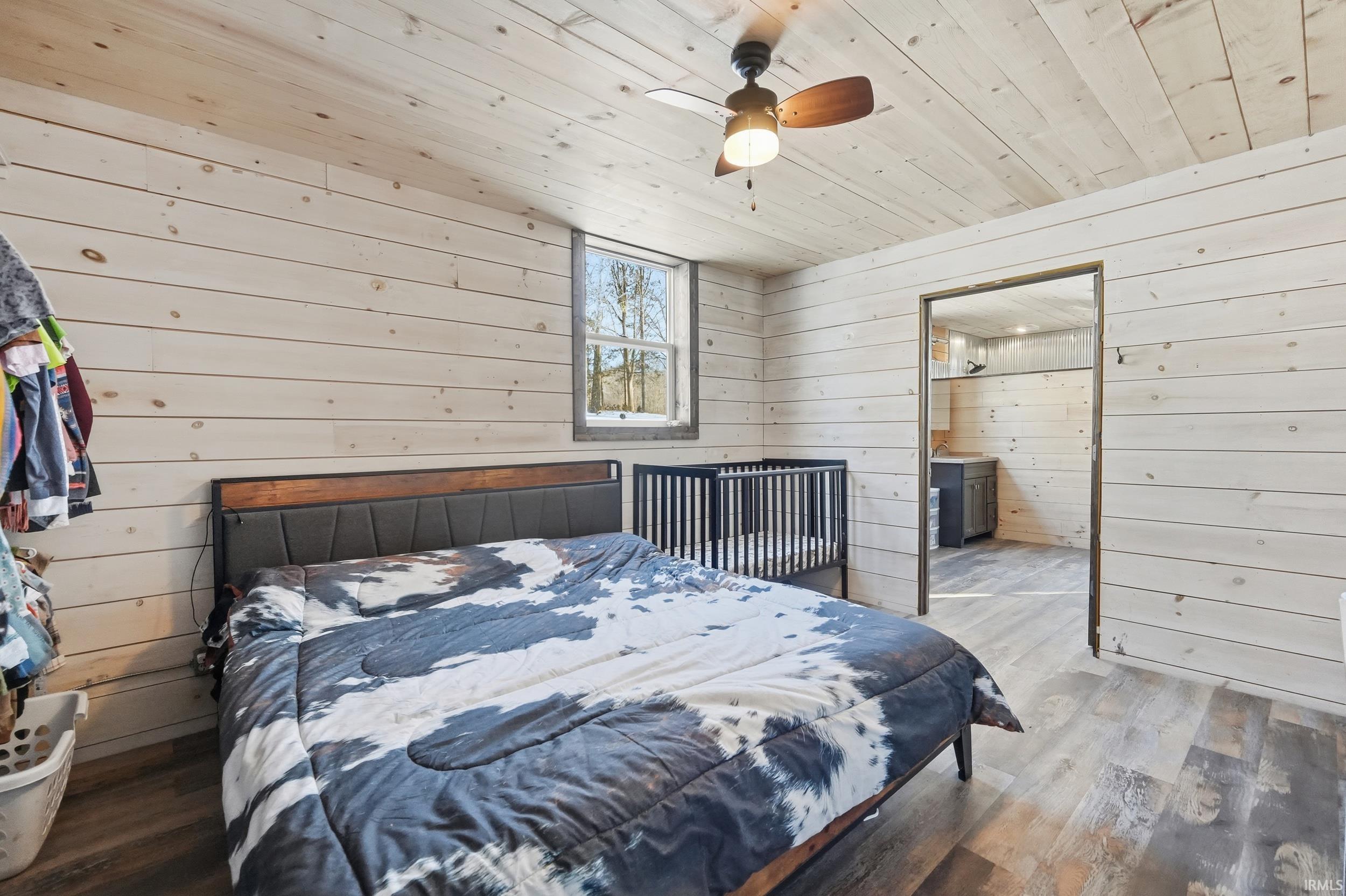 Bedroom featuring wood walls, wooden ceiling, wood finished floors, and ceiling fan
